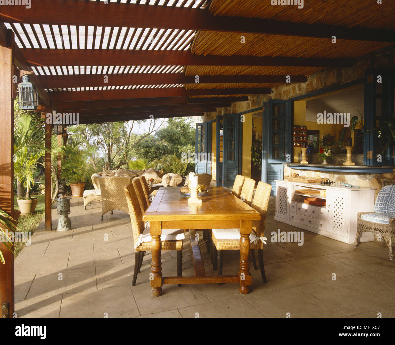 Veranda con tetto in legno pavimenti in pietra tavolo da pranzo e sedie e divani. Foto Stock