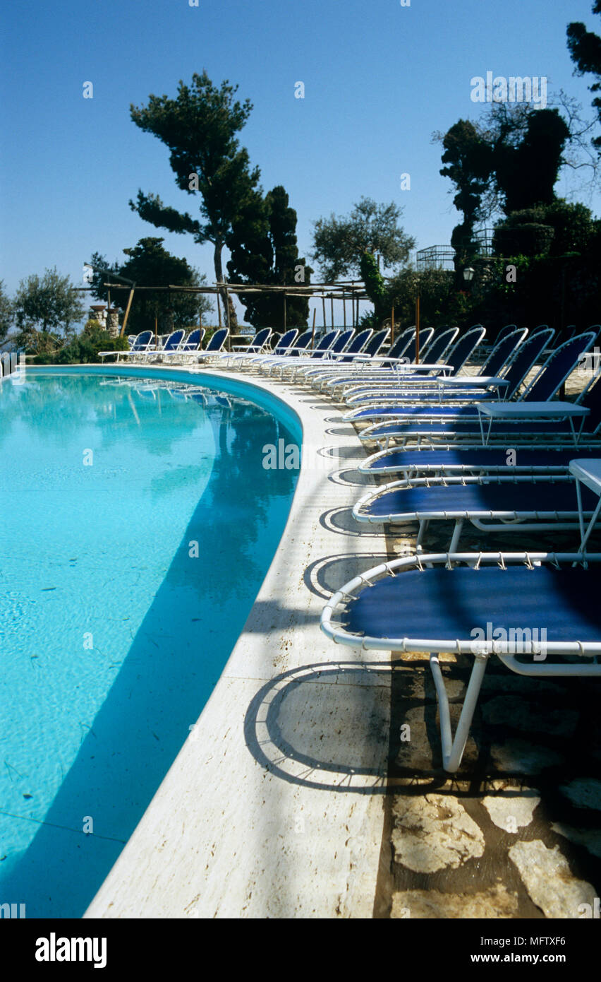 Piscina lettini per prendere il sole in una fila su area pavimentata. Foto Stock