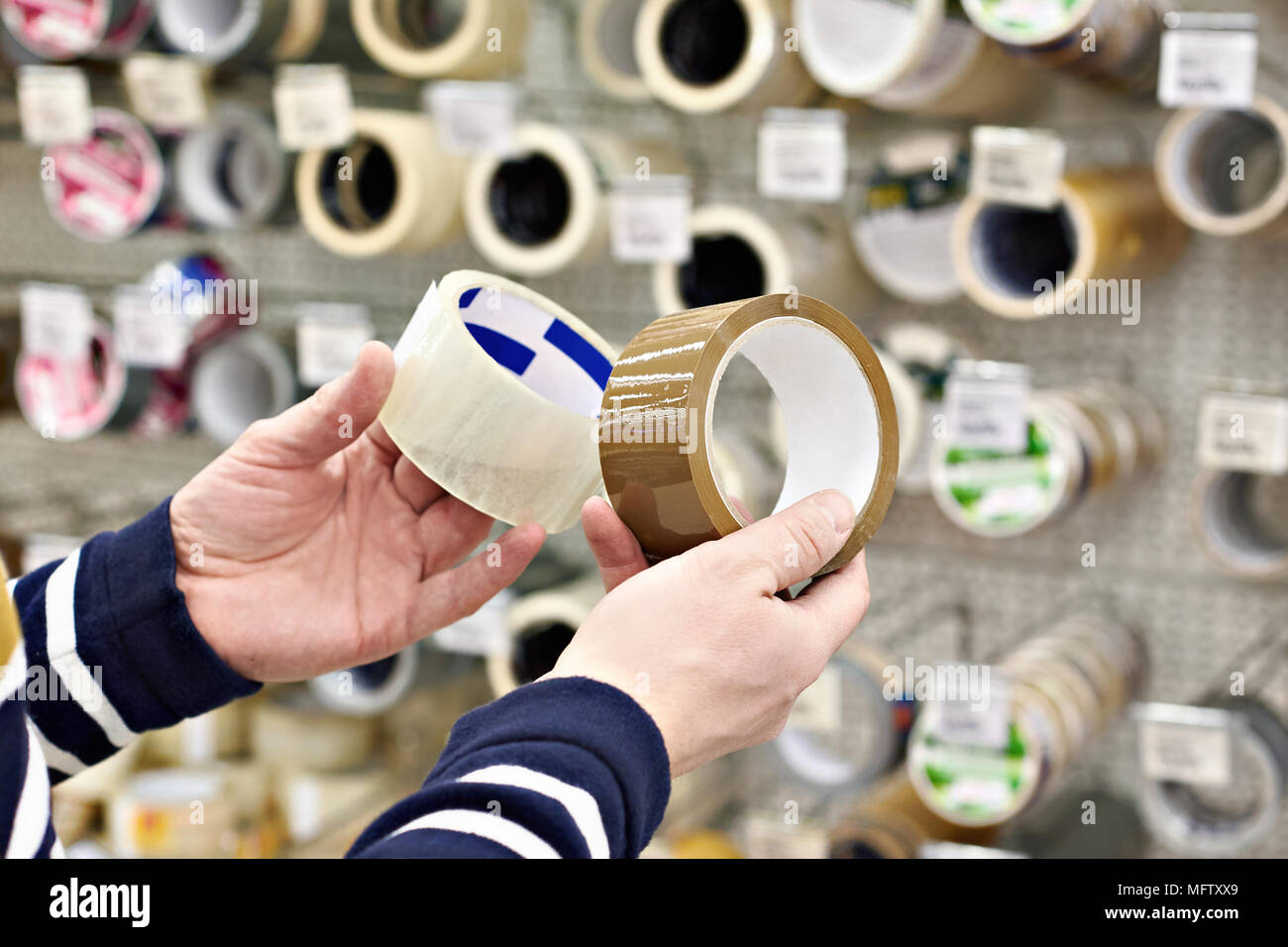 L'uomo acquirente sceglie l'adesivo del nastro per condotti in negozio Foto Stock