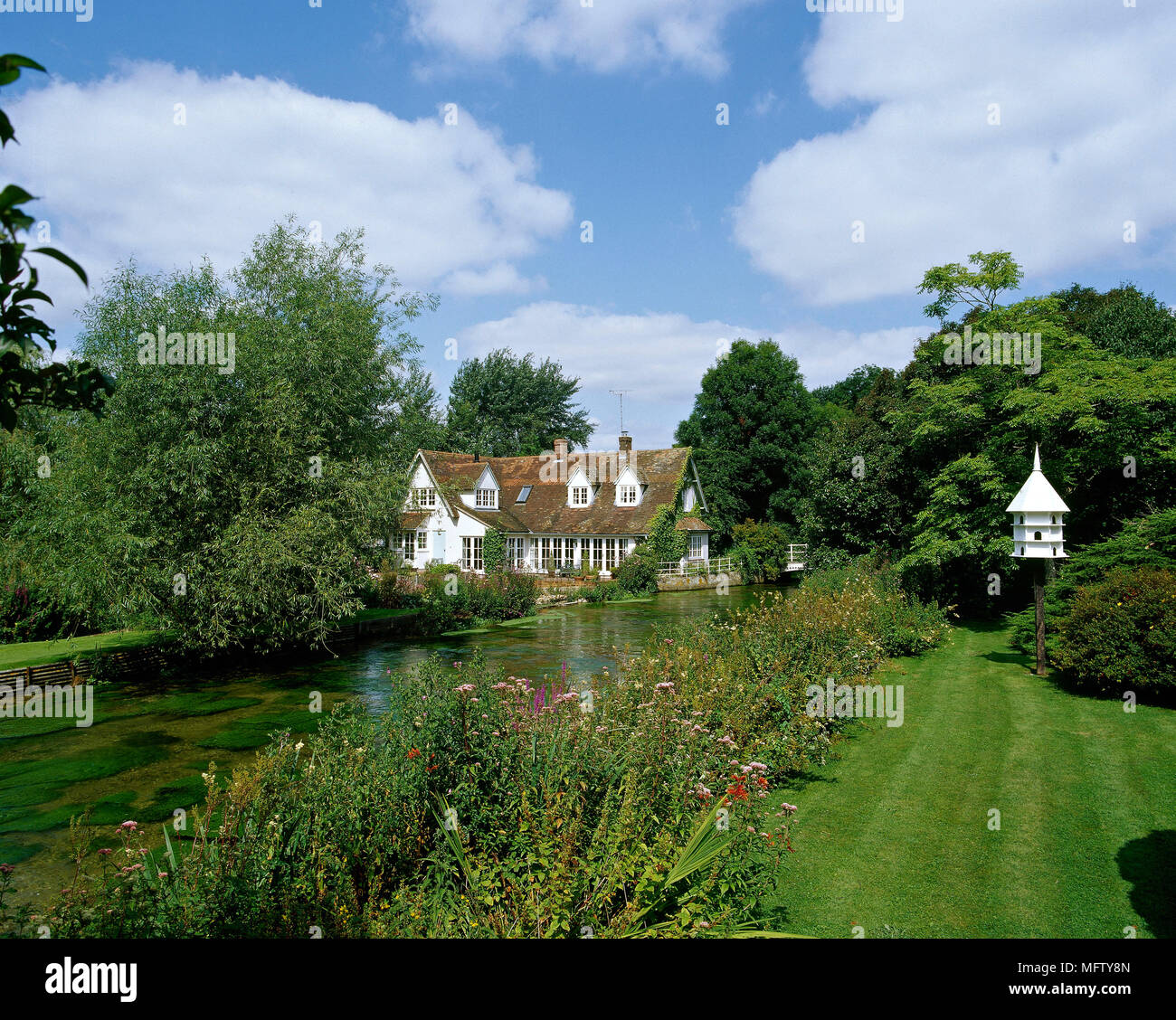 Un esterno di una staccata riverside country house, giardino con laghetto e fiore di frontiera, prato Foto Stock