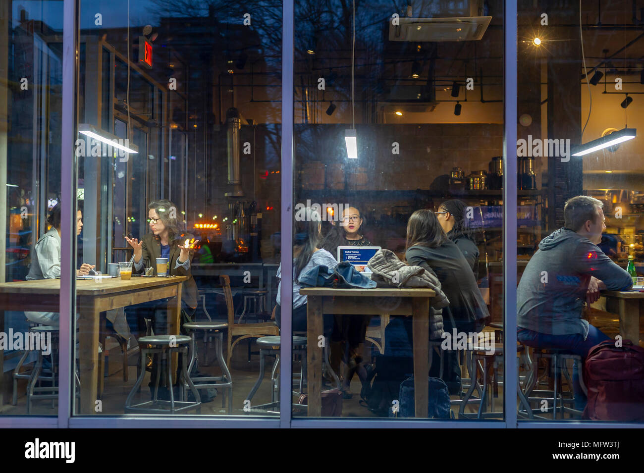 I clienti di sfruttare la connessione wi-fi gratuita in una caffetteria nel quartiere di Chelsea di New York martedì, 24 aprile 2018. La connessione internet wi-fi e le tabelle comunali incoraggiare l uso di coffee shop come co-lo spazio di lavoro. (Â© Richard B. Levine) Foto Stock