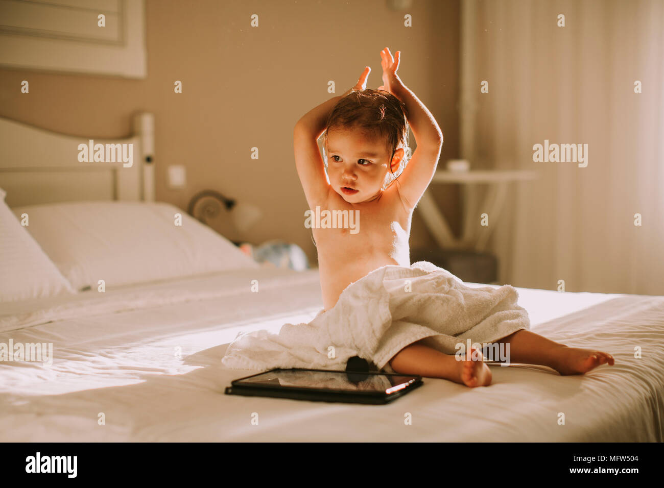 Ricci dolce bambina con un asciugamano sopra il suo corpo bagnato  ubicazione in una camera da letto dopo la doccia o vasca da bagno Foto  stock - Alamy