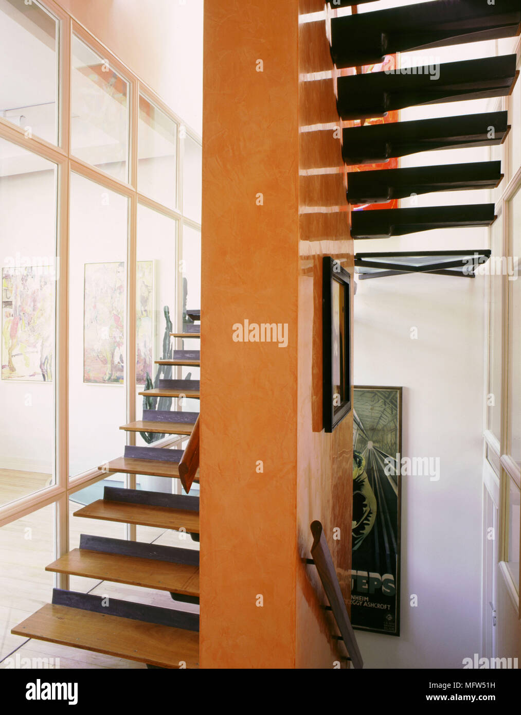 Modern open plan scalinata in legno sospeso pedate orange pareti pannelli in vetro Foto Stock