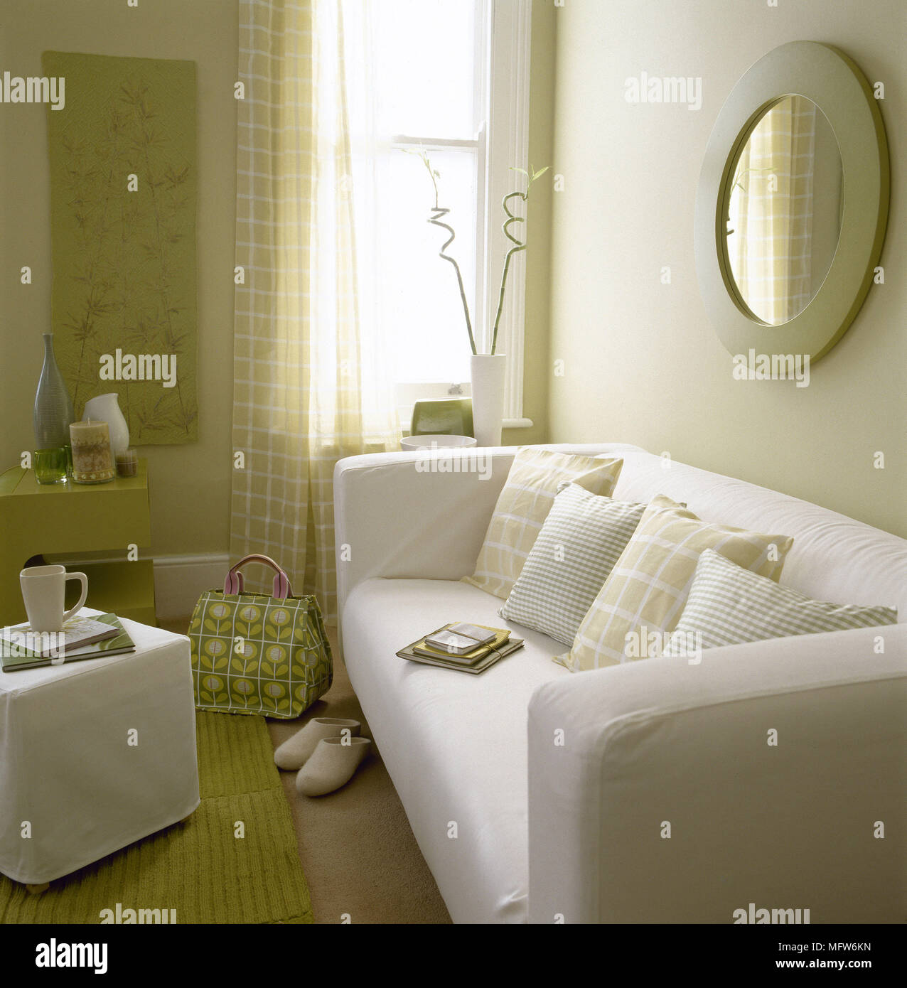 Moderno salotto con divani imbottiti tendaggi slip-coperto poggiapiedi e di  specchio circolare Foto stock - Alamy