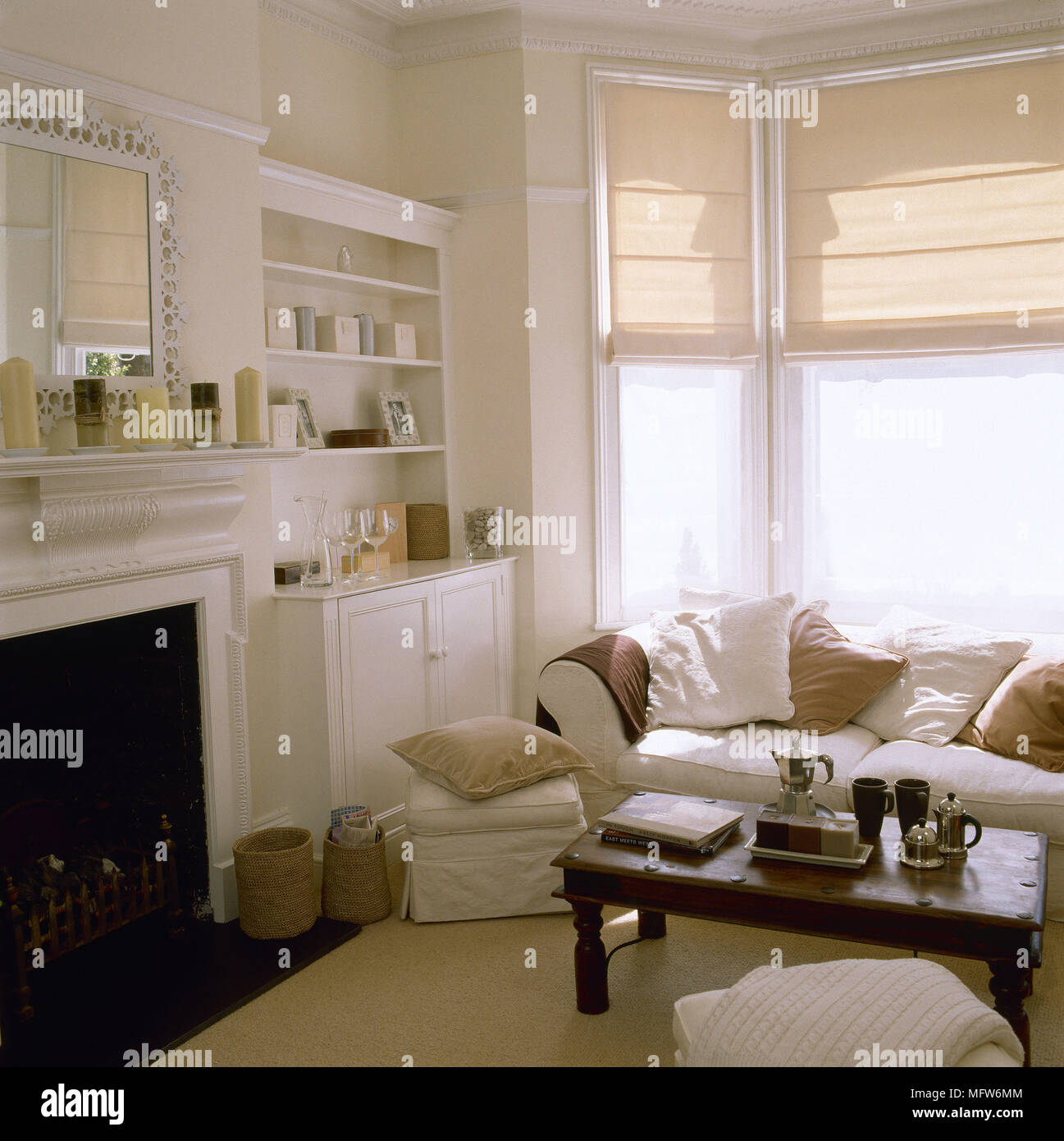 Tradizionale salotto con un caminetto costruito in morbidissima cabinetry divano e sgabello tavolo da caffè in legno e tende su una finestra a bovindo. Foto Stock