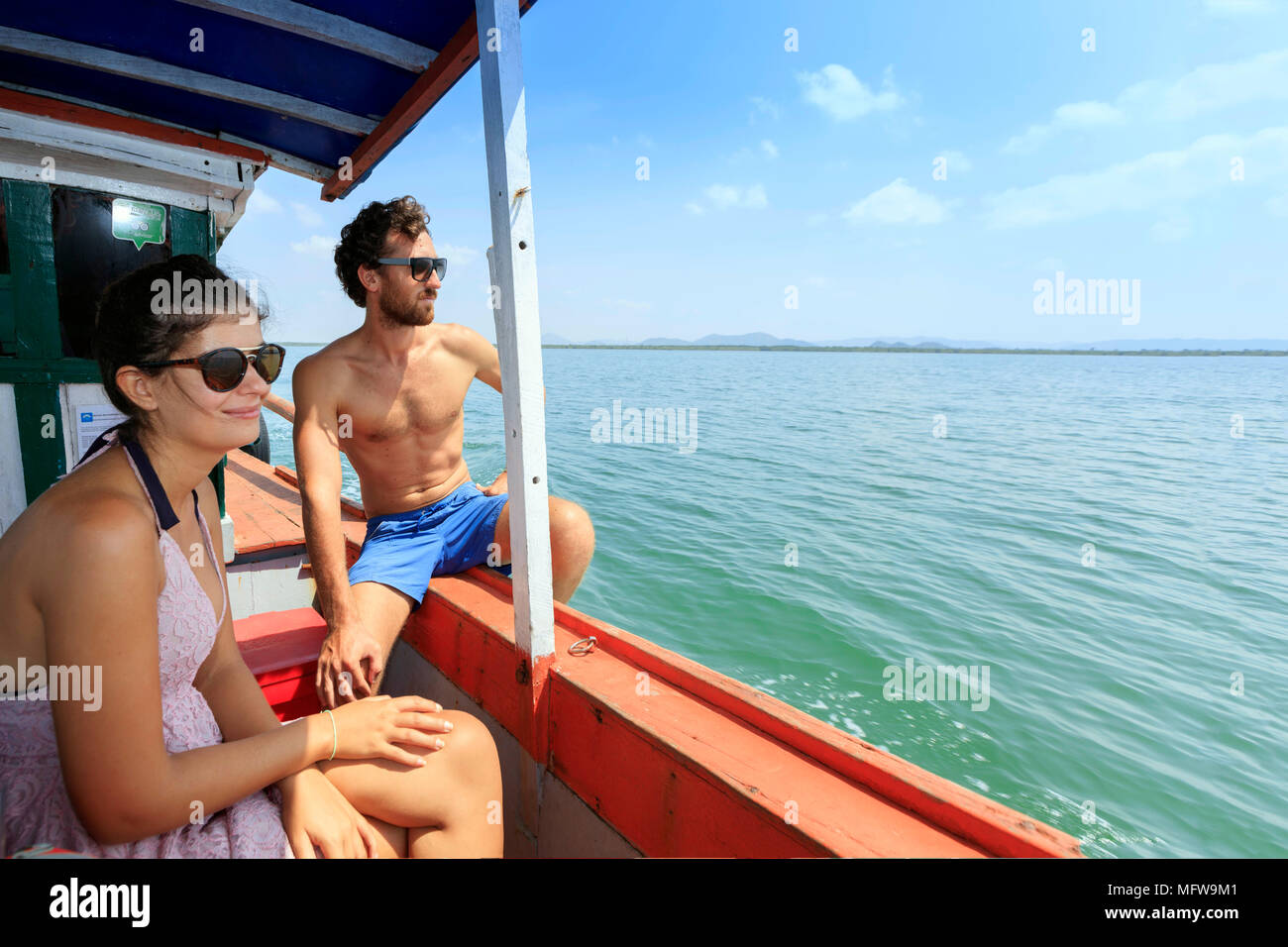 Giovani viaggiatori su una barca per le isole della Cambogia, guardando fuori sopra l'acqua in una giornata di sole. Spazio di copia a destra per una doppia pagina. Foto Stock