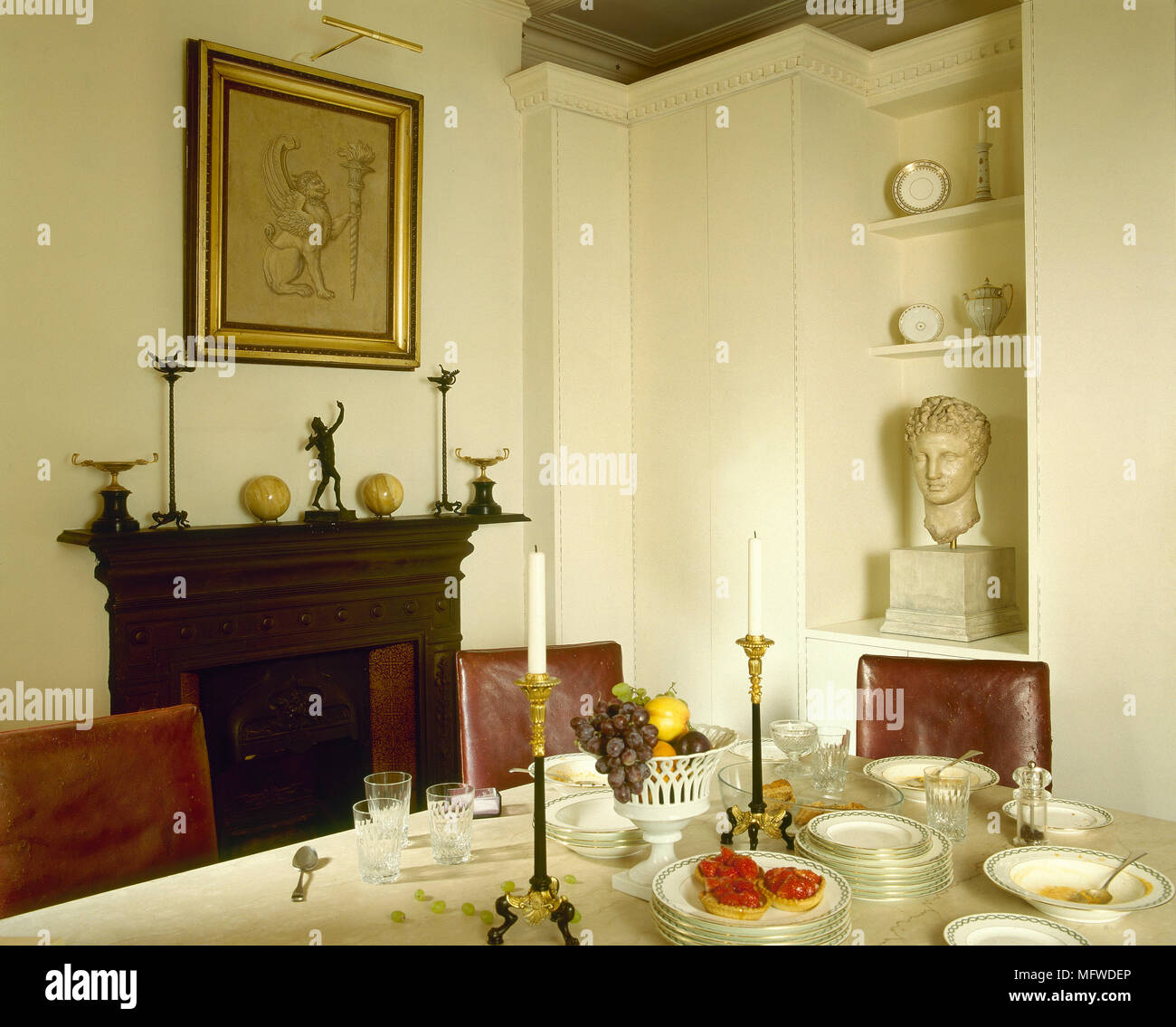 Una tradizionale sala da pranzo con pareti bianche, camino, vasellame, candelabri, Foto Stock