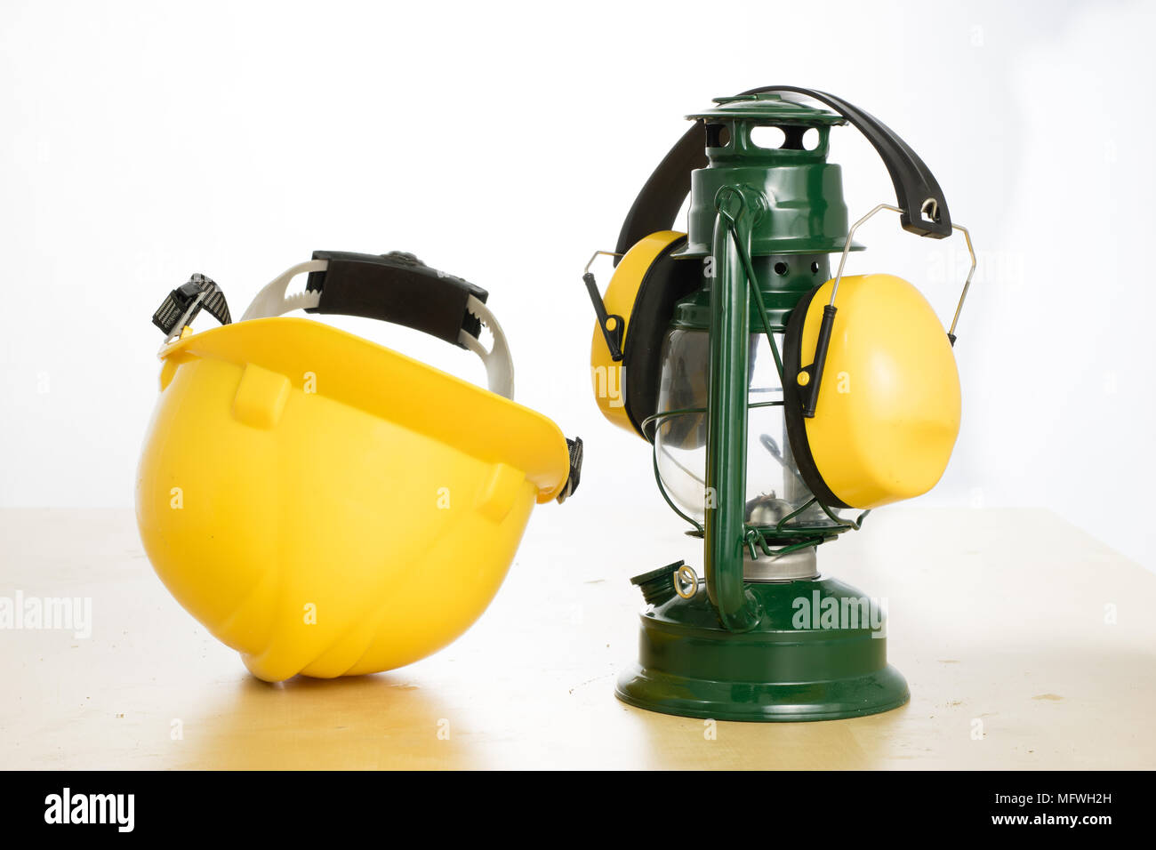 Casco di protezione e lampada a olio su una tavola di legno. Tutela della salute e della sicurezza accessori per lavoratori edili. Bianco sfondo isolato. Foto Stock