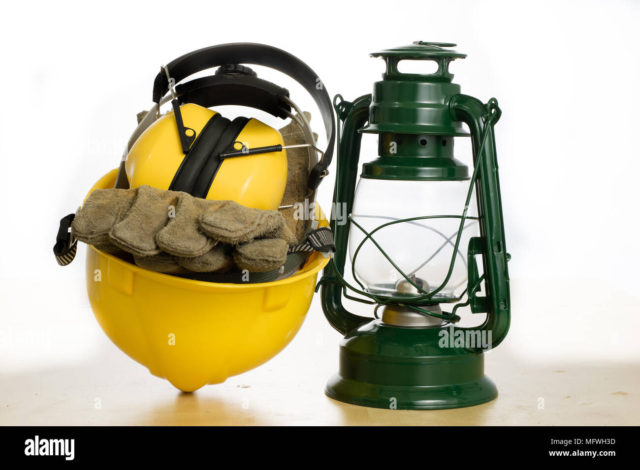 Casco di protezione e lampada a olio su una tavola di legno. Tutela della salute e della sicurezza accessori per lavoratori edili. Bianco sfondo isolato. Foto Stock