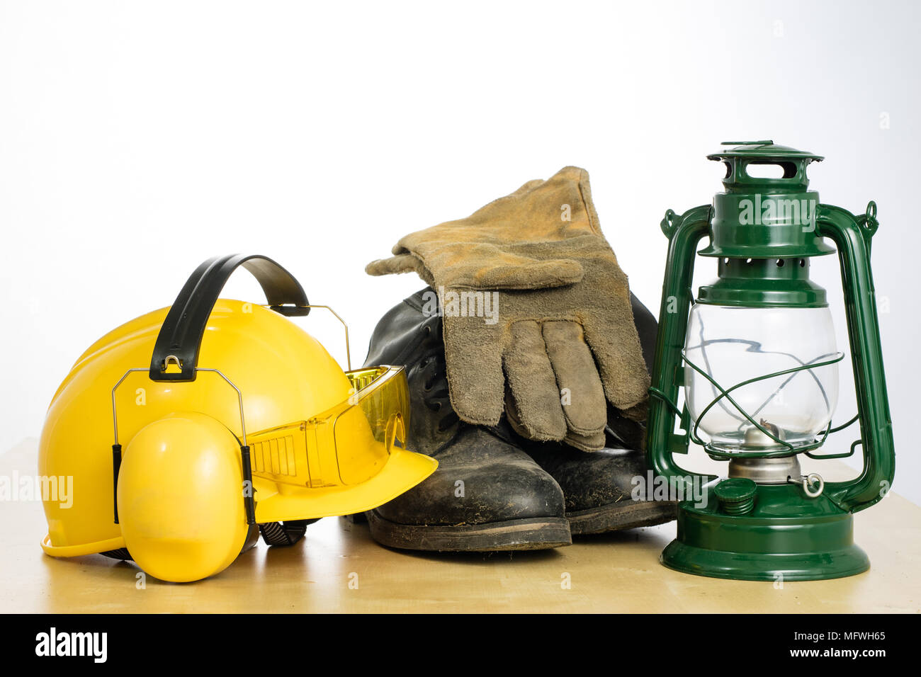 Casco di protezione e lampada a olio su una tavola di legno. Tutela della salute e della sicurezza accessori per lavoratori edili. Bianco sfondo isolato. Foto Stock