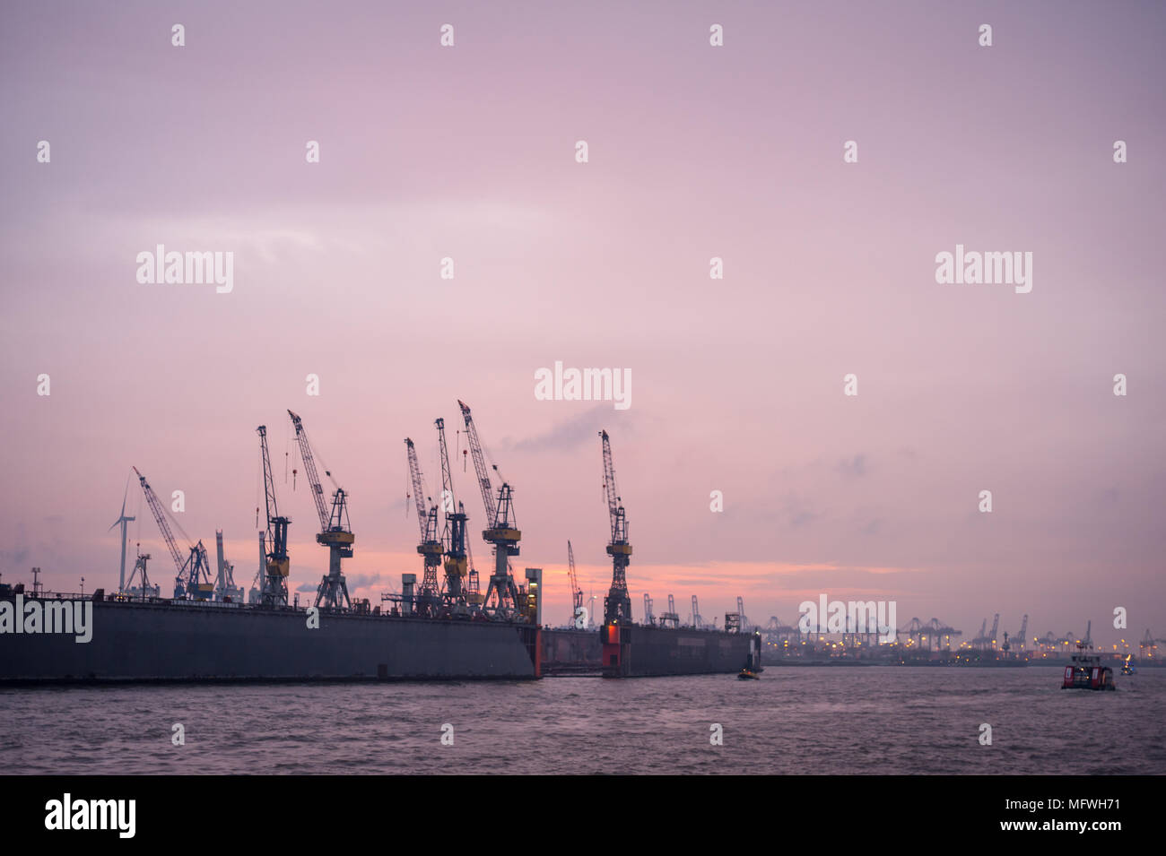Serata di scena nel porto di Amburgo, con cantiere, gru e di terminal per container e navi da crociera sul fiume Elba. Foto Stock
