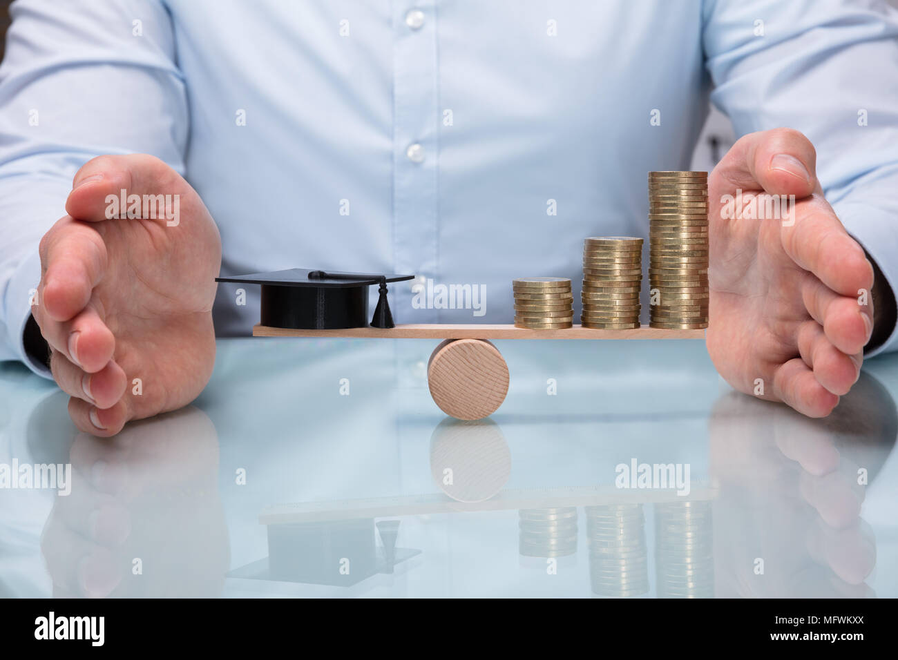 Close-up di una mano la protezione di equilibrio tra la laurea Hat e aumentando le monete impilate su altalena Foto Stock