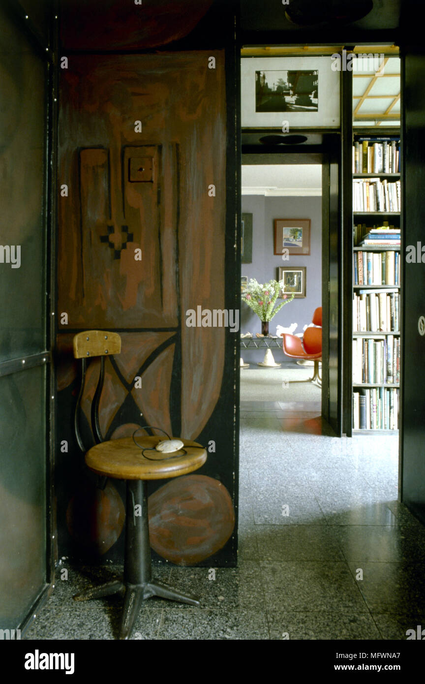 Spazio eclettico con pavimento di linoleum, sgabello in legno, decorativi effetti di pittura, e una porta di camere adiacenti. Foto Stock