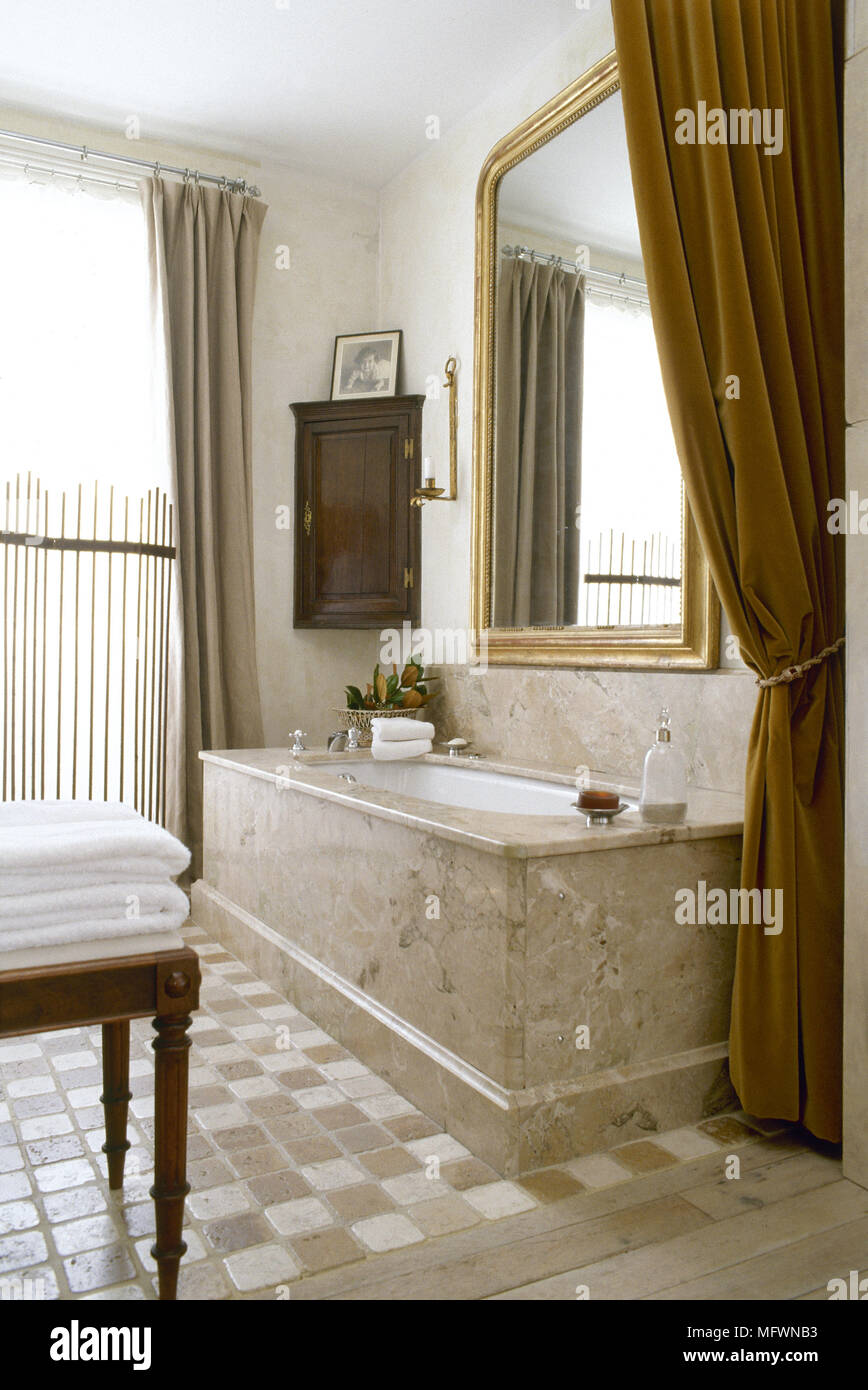 Bagno tradizionale a scacchi con pavimento in piastrelle e vasca da bagno  in una cornice di marmo, tendaggi in velluto, specchio con cornice dorata e  luminosa finestra Foto stock - Alamy