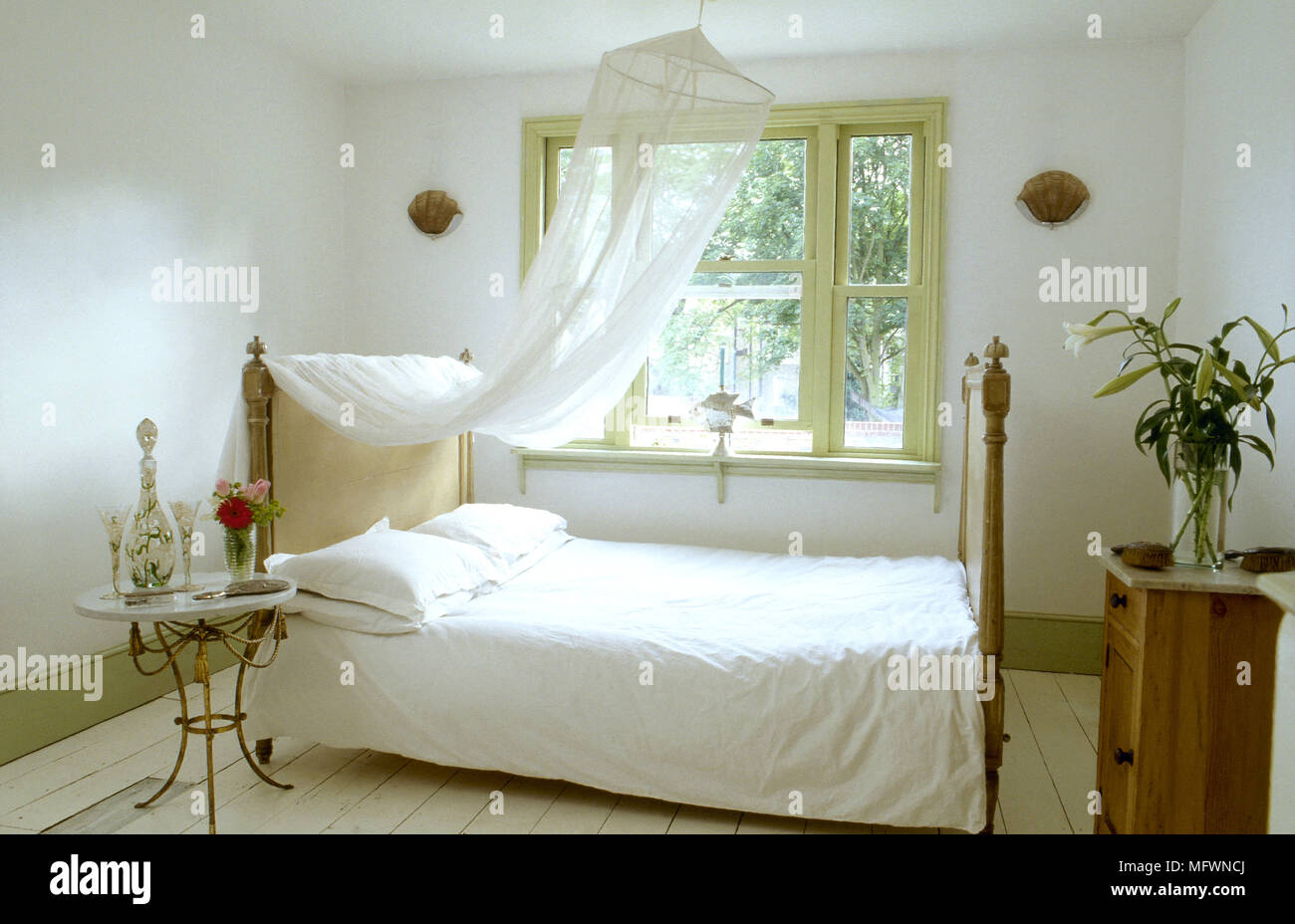 Romantica camera da letto con baldacchino a strapiombo su un letto doppio, piano in marmo comodino e una finestra piena di sole. Foto Stock