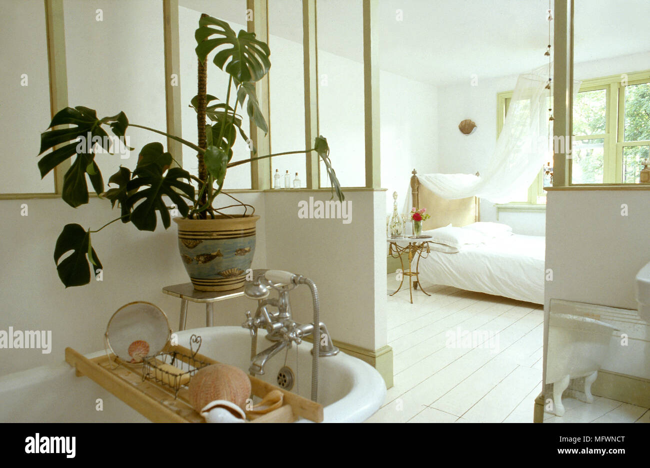 Romantico, open master suite con un free standing roll top vasca, letto a baldacchino, imbiancato tavoloni e luminosa finestra. Foto Stock