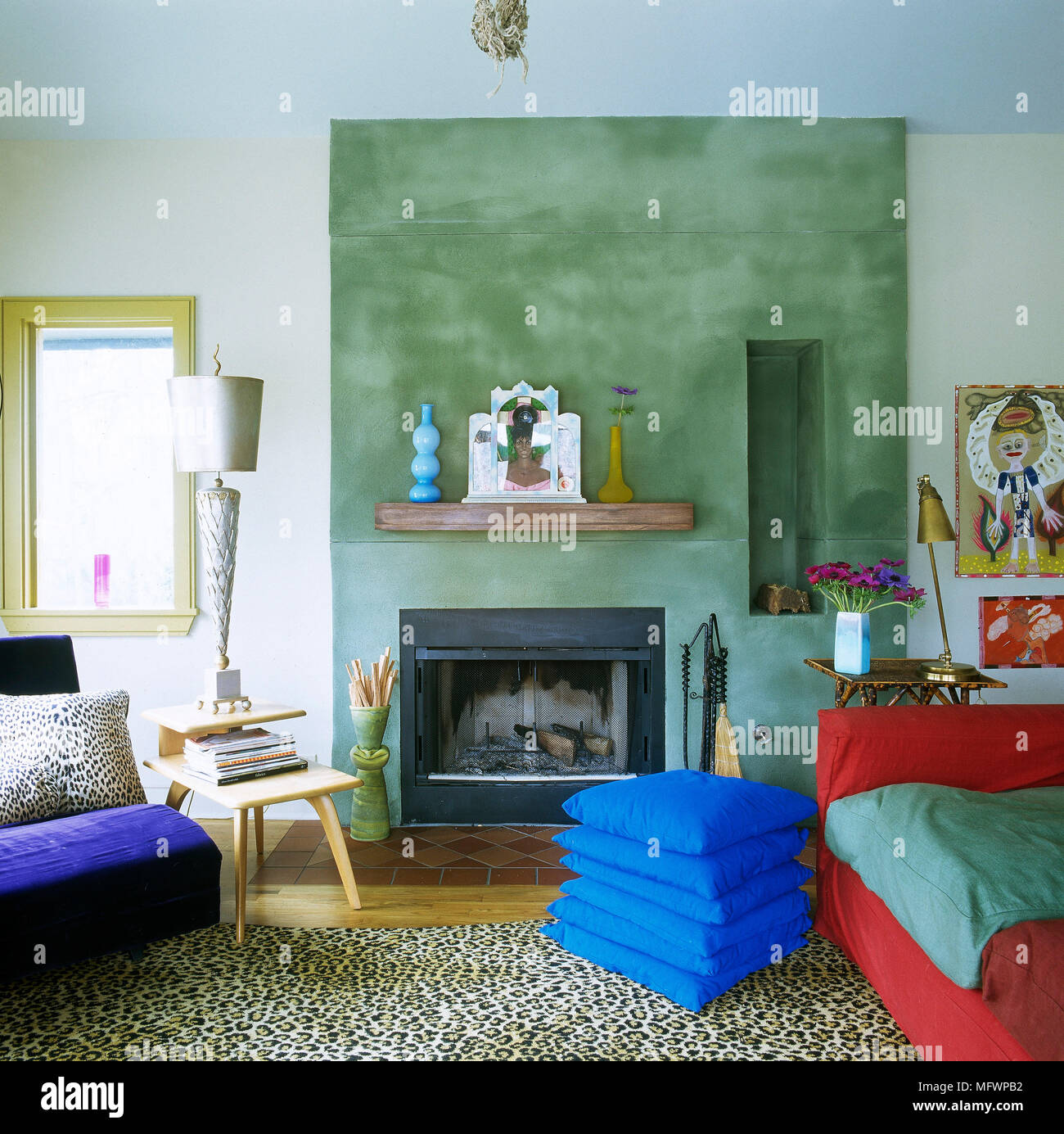 Moderno salotto con camino impostato in funzione di verde a parete, pila di  cuscini blu Foto stock - Alamy