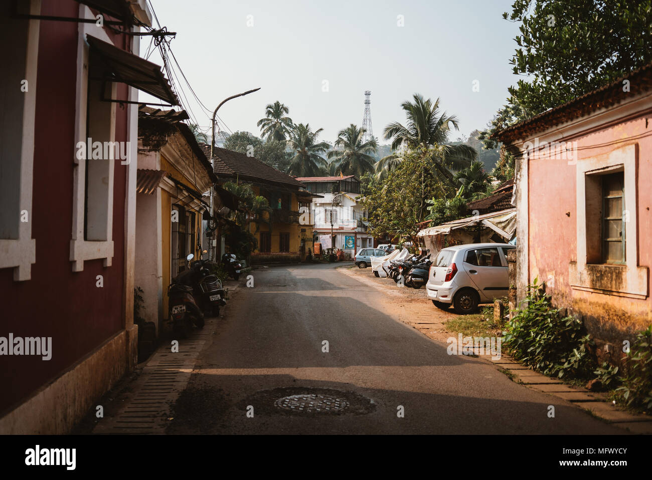 Tranquilla strada residenziale foderato con vetture in Goa, India Foto Stock