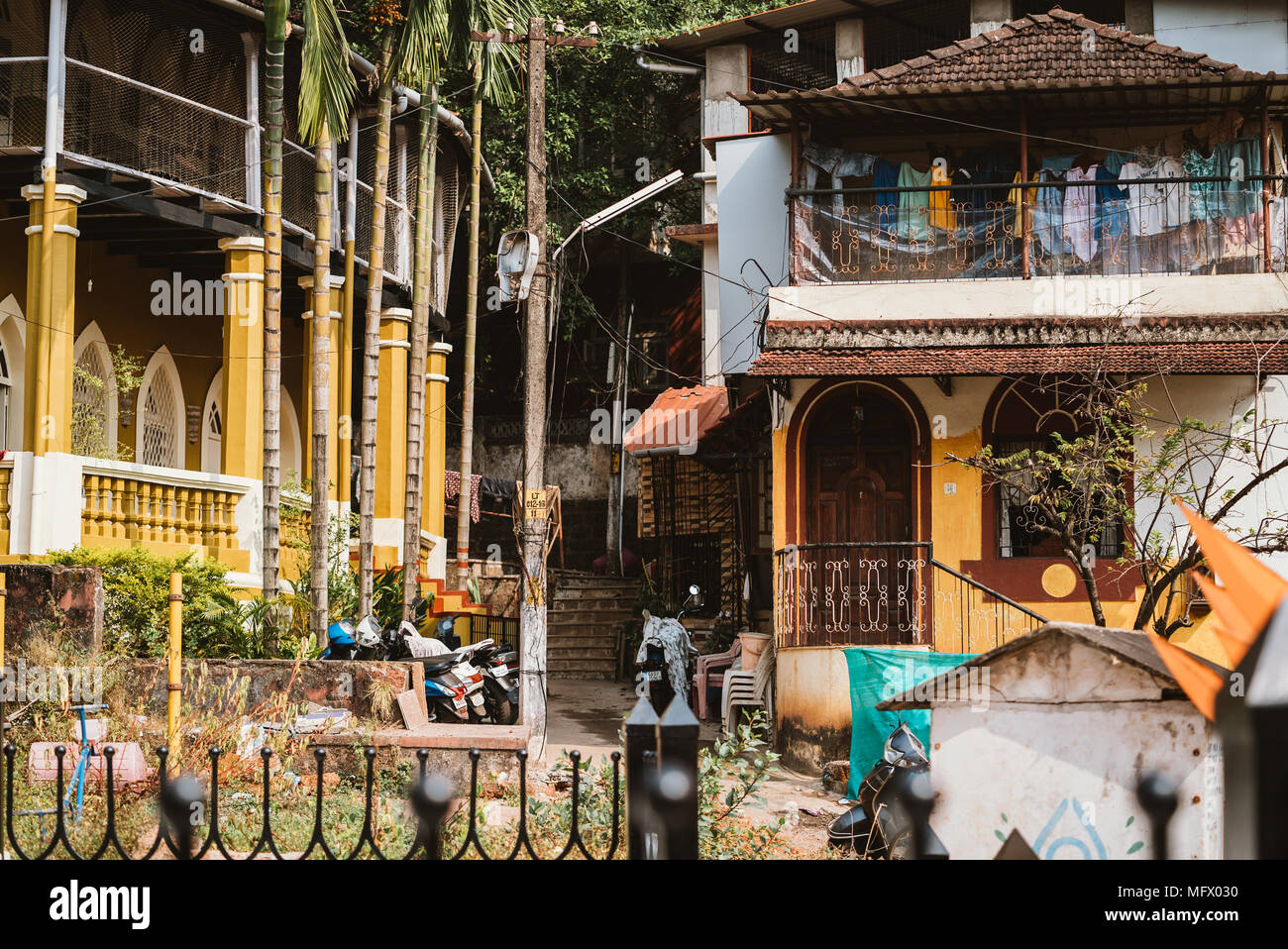 Case con stendibiancheria sulla linea e la scala. Goa, India Foto Stock
