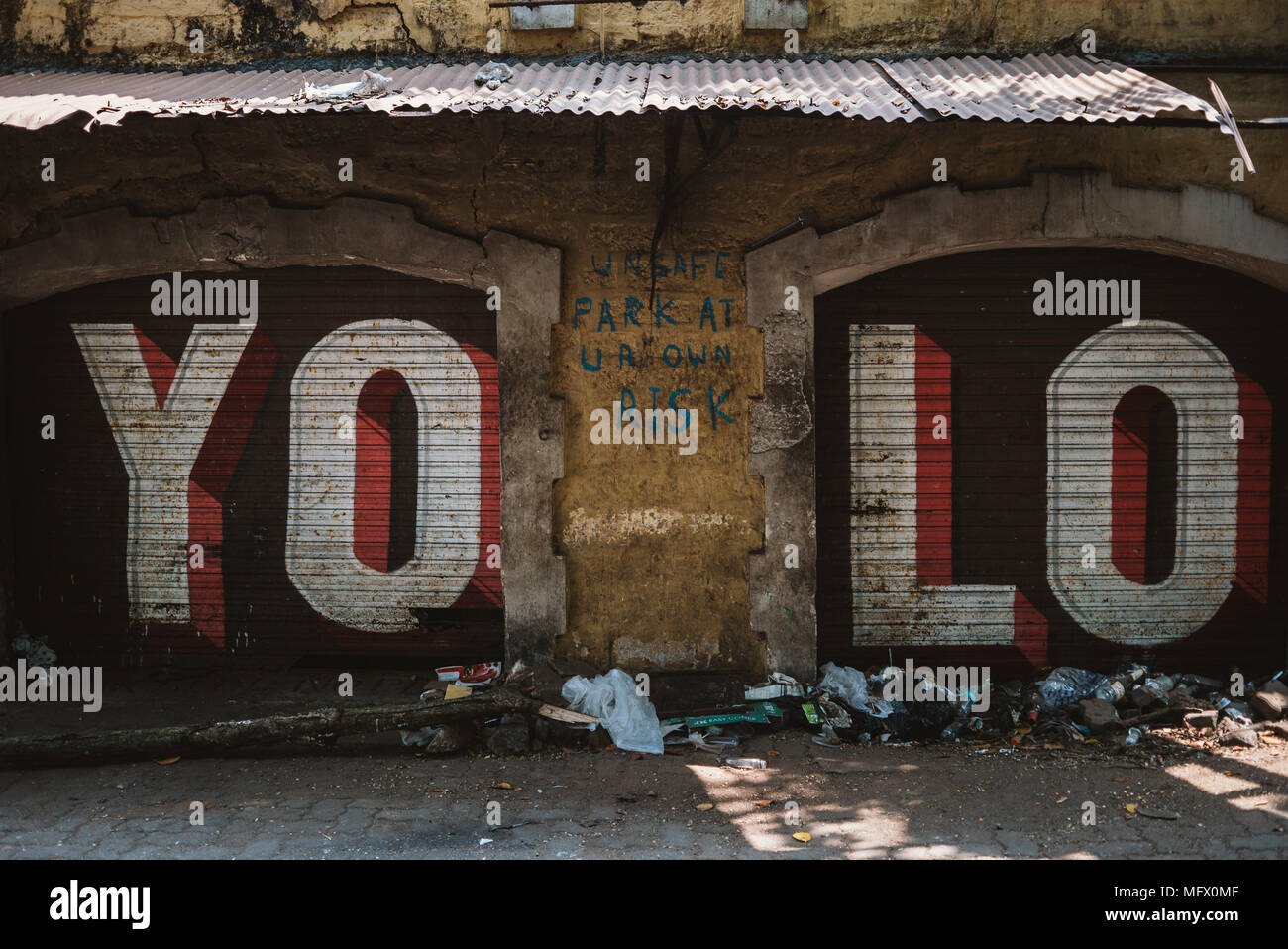 YOLO graffiti sulle porte di garage con cestino in Goa, India Foto Stock