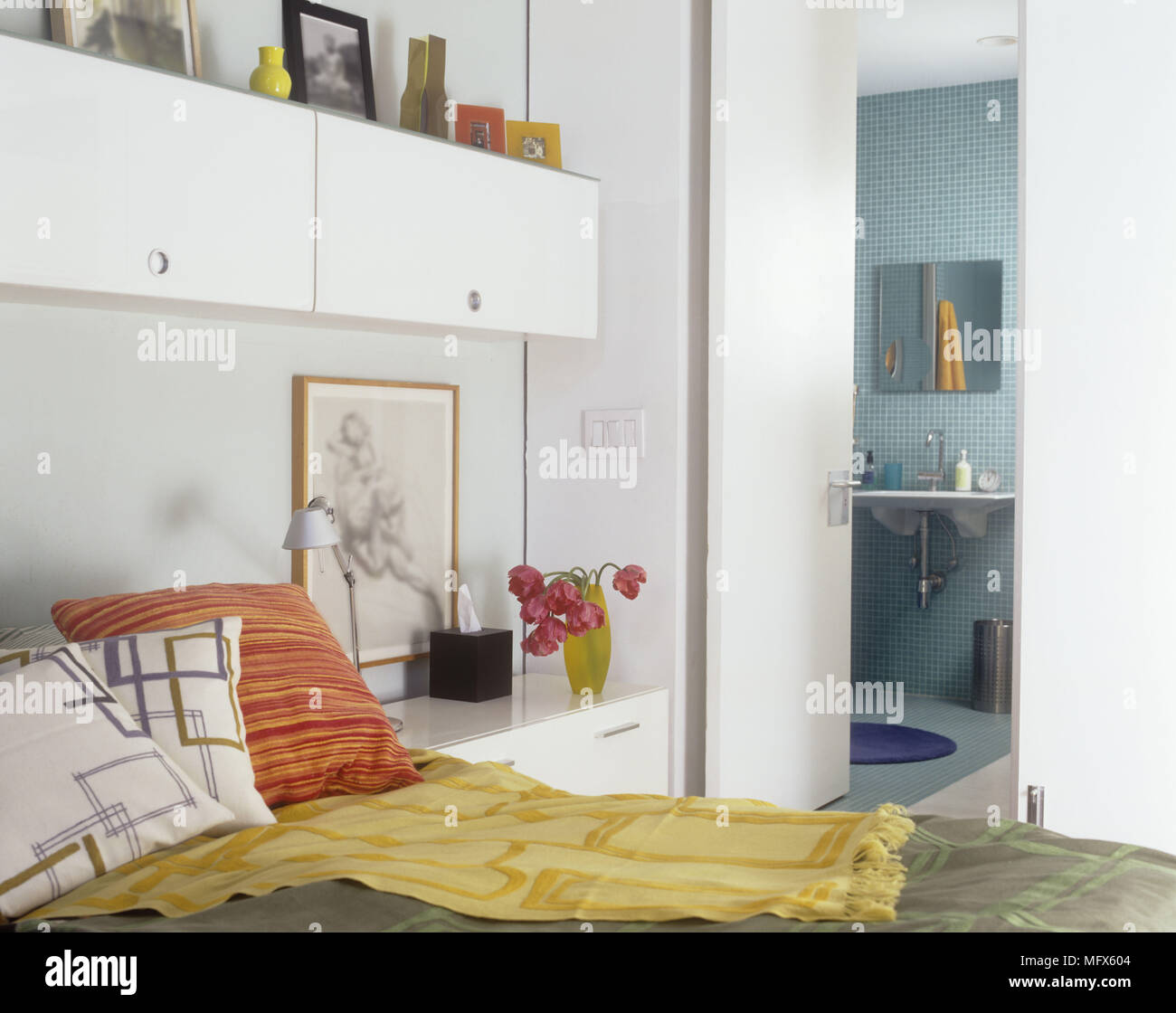 Un dettaglio di una moderna camera da letto con letto matrimoniale e  cuscini colorati porta aperta al bagno Foto stock - Alamy