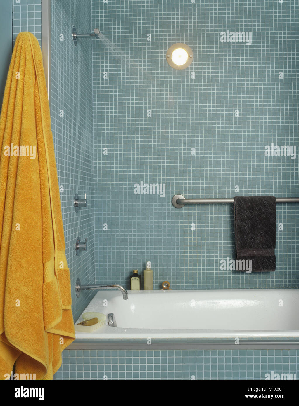 Un moderno bagno blu pareti piastrellate con un mosaico di piastrelle bagno chrome tocca i raccordi portasciugamani asciugamano arancione Foto Stock