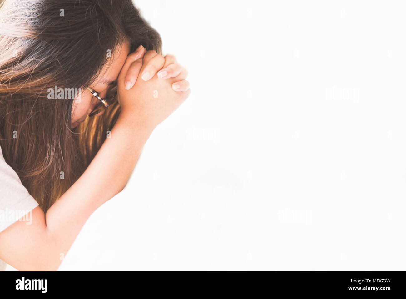 Donna orante sul letto la mattina.adolescente donna orante a mano,mani giunte in preghiera sul letto la mattina concetto per la fede e la spiritualità di un Foto Stock