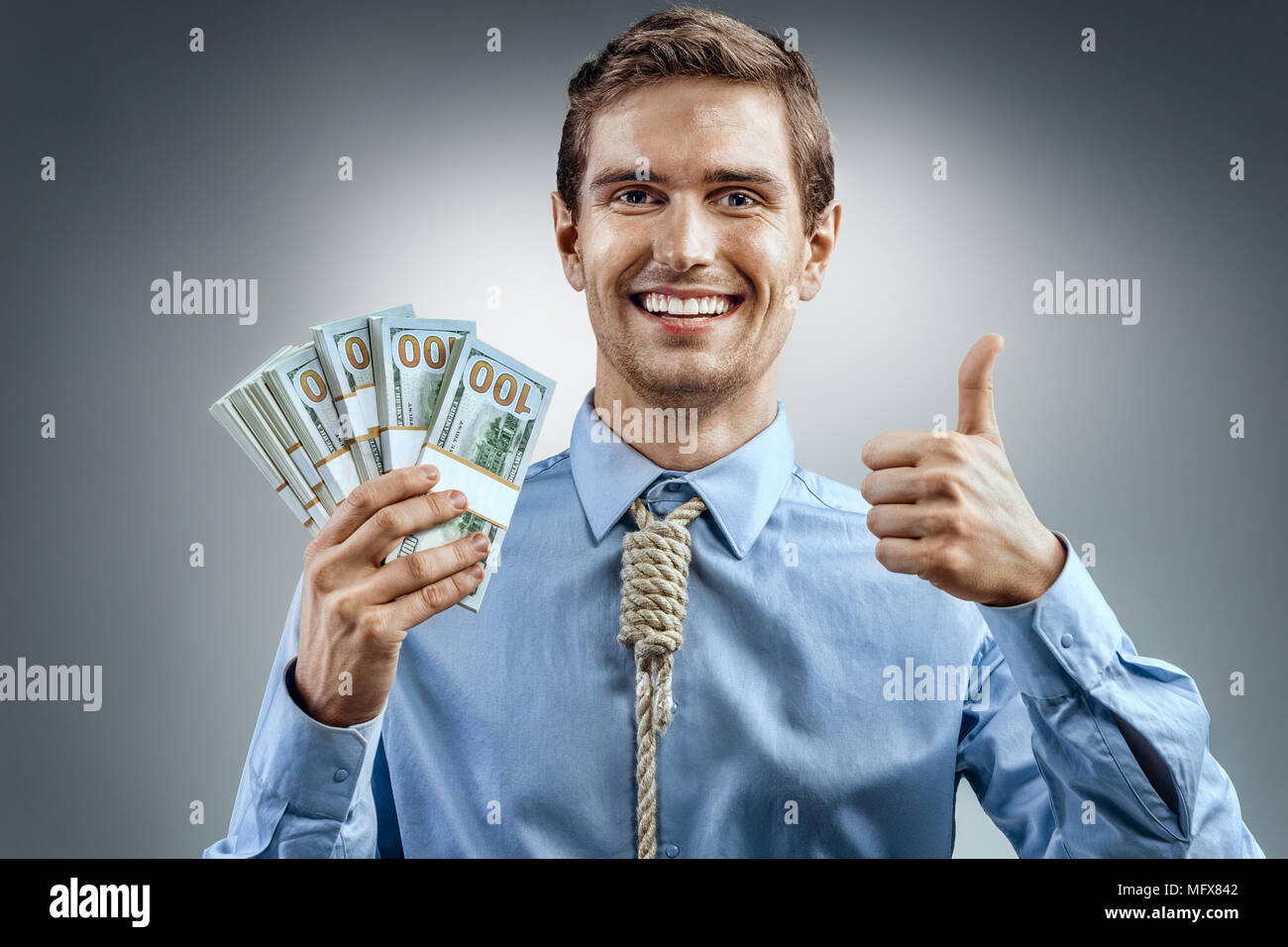 Uomo con denaro contante e mostrando il pollice verso l'alto. Foto di uomo sorridente in maglietta blu e cravatta in forma di ansa sul suo collo su sfondo grigio Foto Stock
