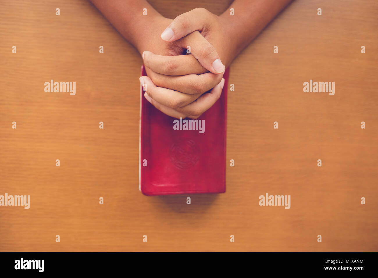 Vista superiore dell'uomo che prega sulla Sacra Bibbia in mattinata.ragazzo adolescente mano con la Bibbia pregando,mani giunte in preghiera in una Sacra Bibbia in chiesa il concetto di Foto Stock