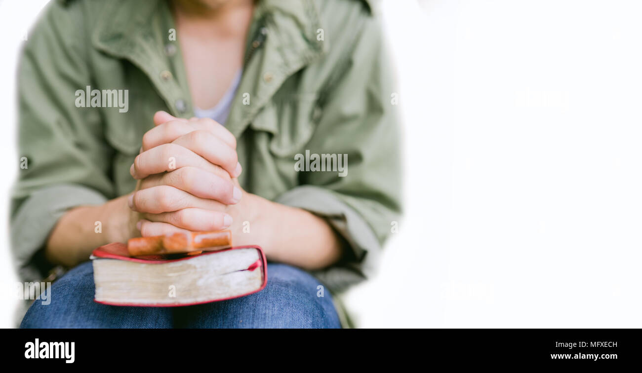 Uomo che prega sulla Sacra Bibbia in mattinata.ragazzo adolescente mano con la Bibbia pregando,mani giunte in preghiera in una Sacra Bibbia nel concetto di chiesa per la fede, spir Foto Stock
