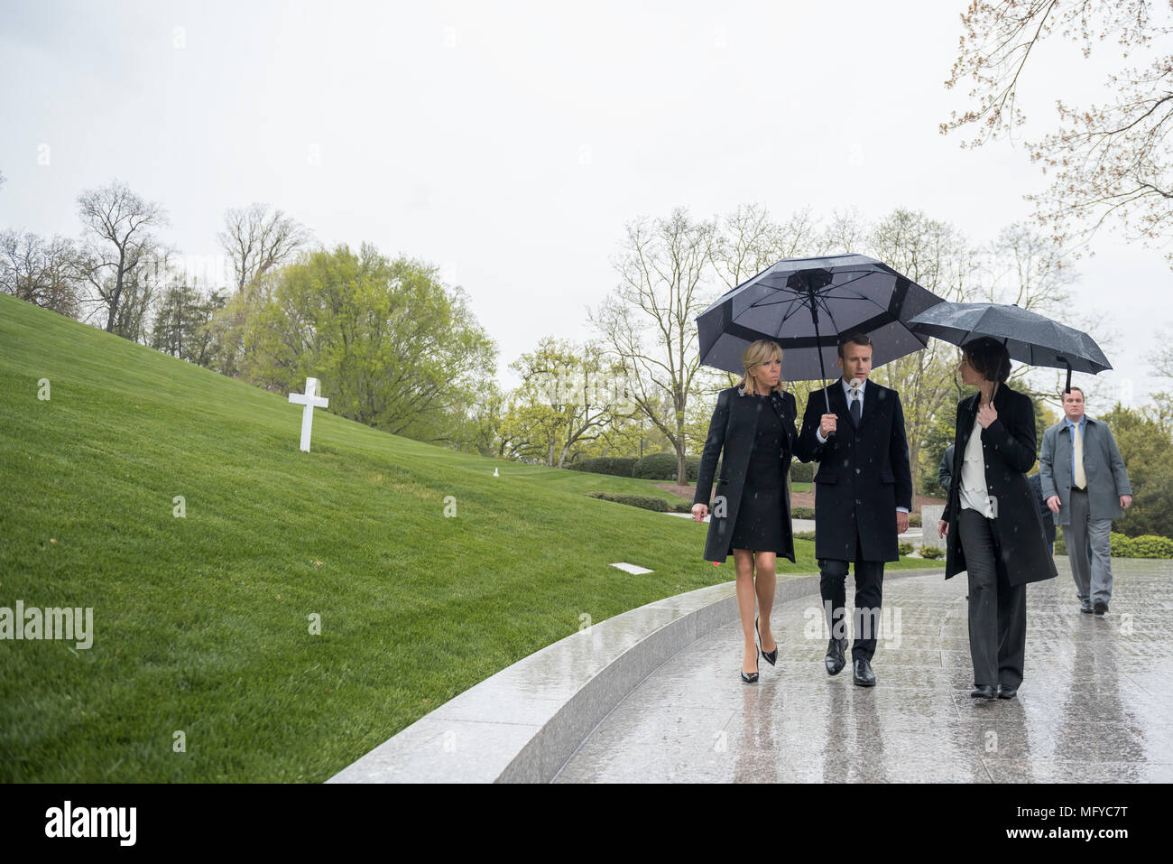 Il Presidente francese Emmanuel Macron, centro e da sua moglie Brigitte Macron, sono scortati dalla soprintendente Katharine Kelley, destra durante una visita al recinto di Robert F. Kennedy in un giorno di pioggia al Cimitero Nazionale di Arlington, Aprile 24, 2018 in Arlington, Virginia. Foto Stock
