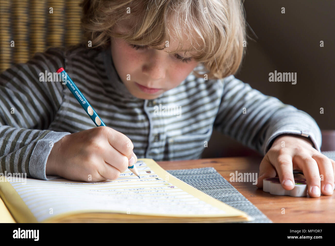 Il ragazzo, scuola elementare studente, 8 anni, impara a scuola a casa, non i compiti, esercizi di scrittura Foto Stock