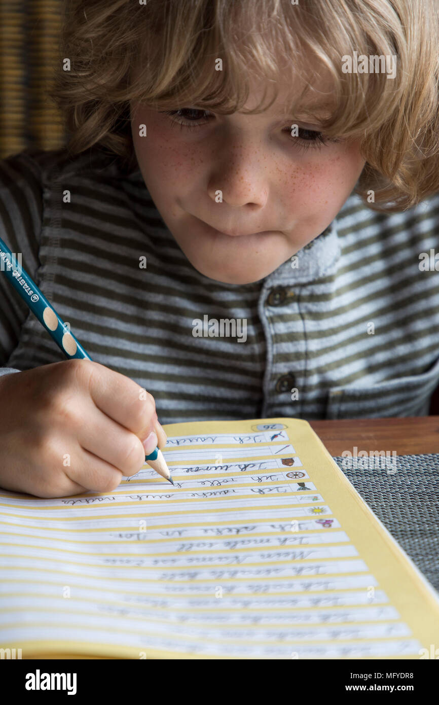 Il ragazzo, scuola elementare studente, 8 anni, impara a scuola a casa, non i compiti, esercizi di scrittura Foto Stock