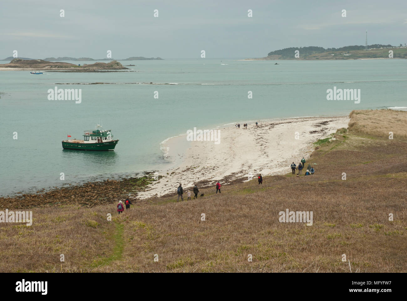 Vista su isola di Sansone che mostra una spiaggia sabbiosa e persone che fanno la loro strada giù per la collina fino al traghetto di attesa. Foto Stock