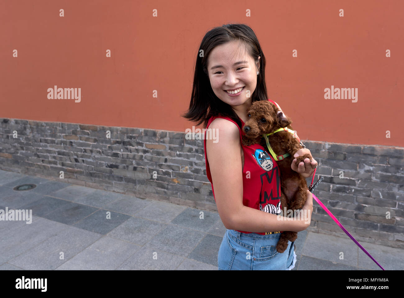 Giovane donna abbraccia il suo cucciolo mentre si visita il parco della città, Xilinhot, Mongolia Interna, Cina Foto Stock