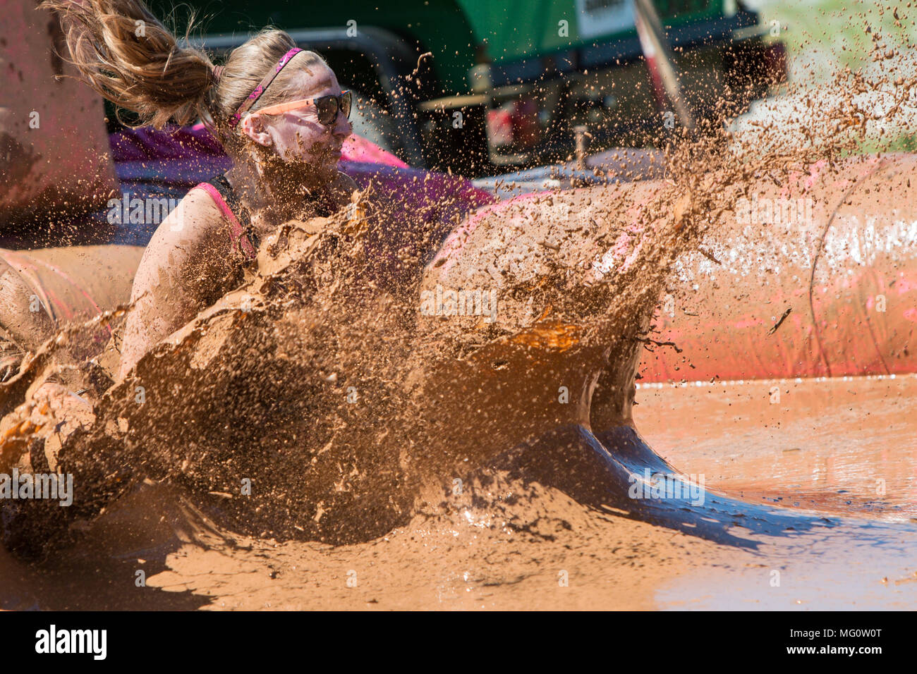 Una donna crea un grande splash di acqua fangosa come lei atterra in un pozzo del fango alla ragazza sporca di fango eseguire ostacolo corso su Aprile 23, 2016 in Hampton, GA. Foto Stock