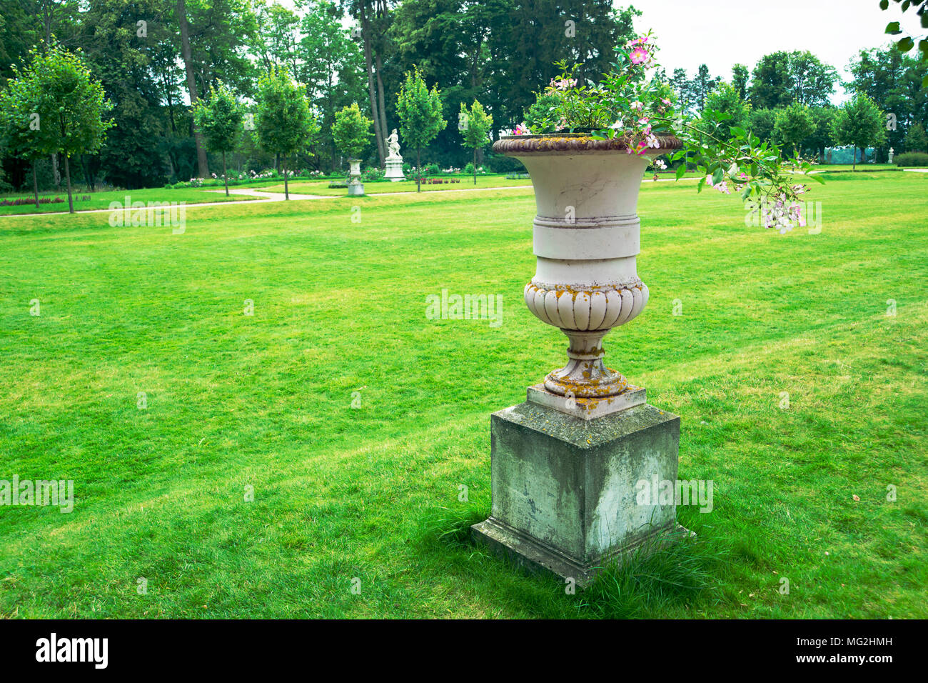Rifilato erba prato del classico stile francese parco con focus sul vaso di pietra scultura di estate Foto Stock