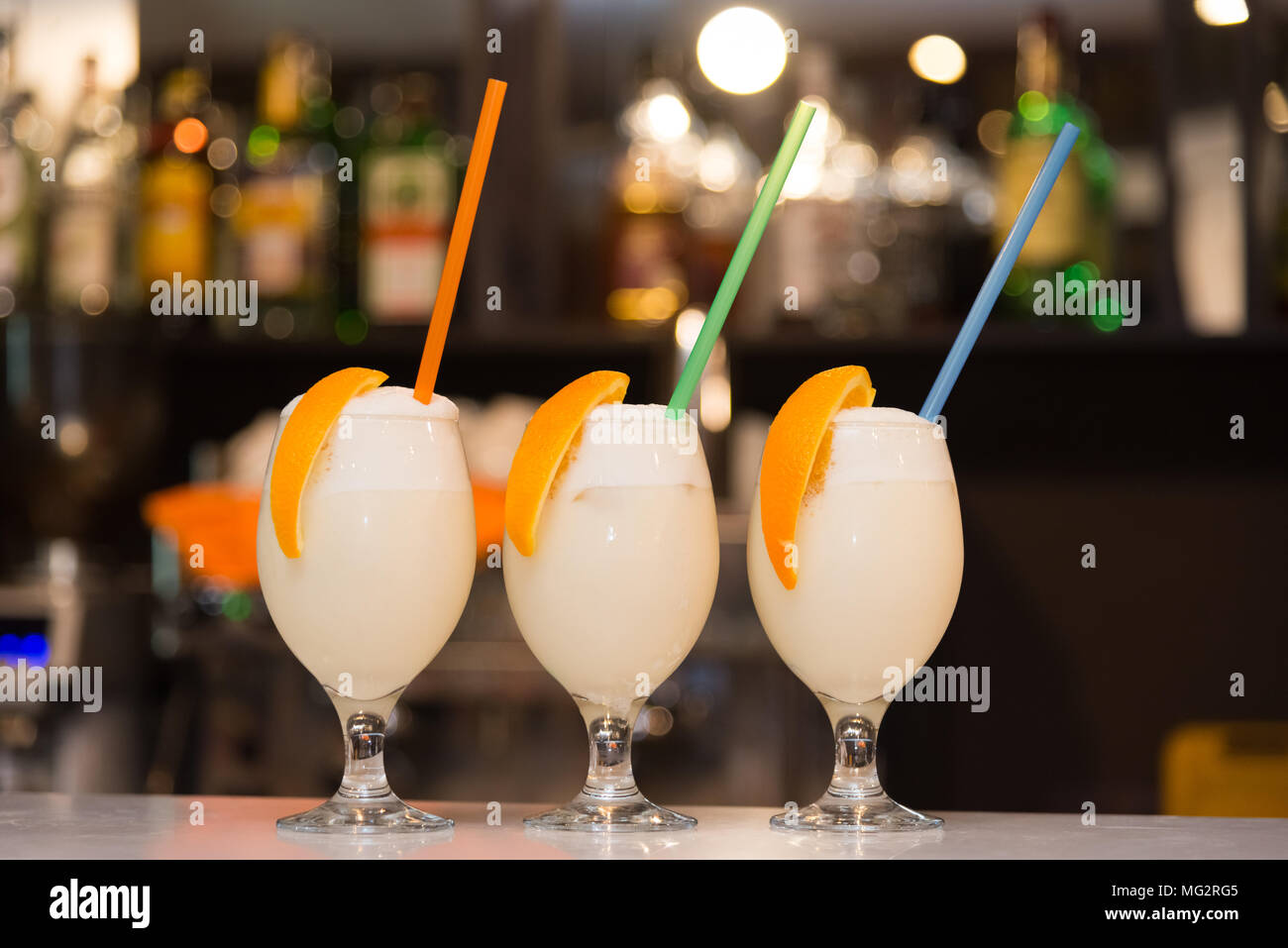 Tre frappè con arancia e cannucce stand sul bancone del bar Foto Stock