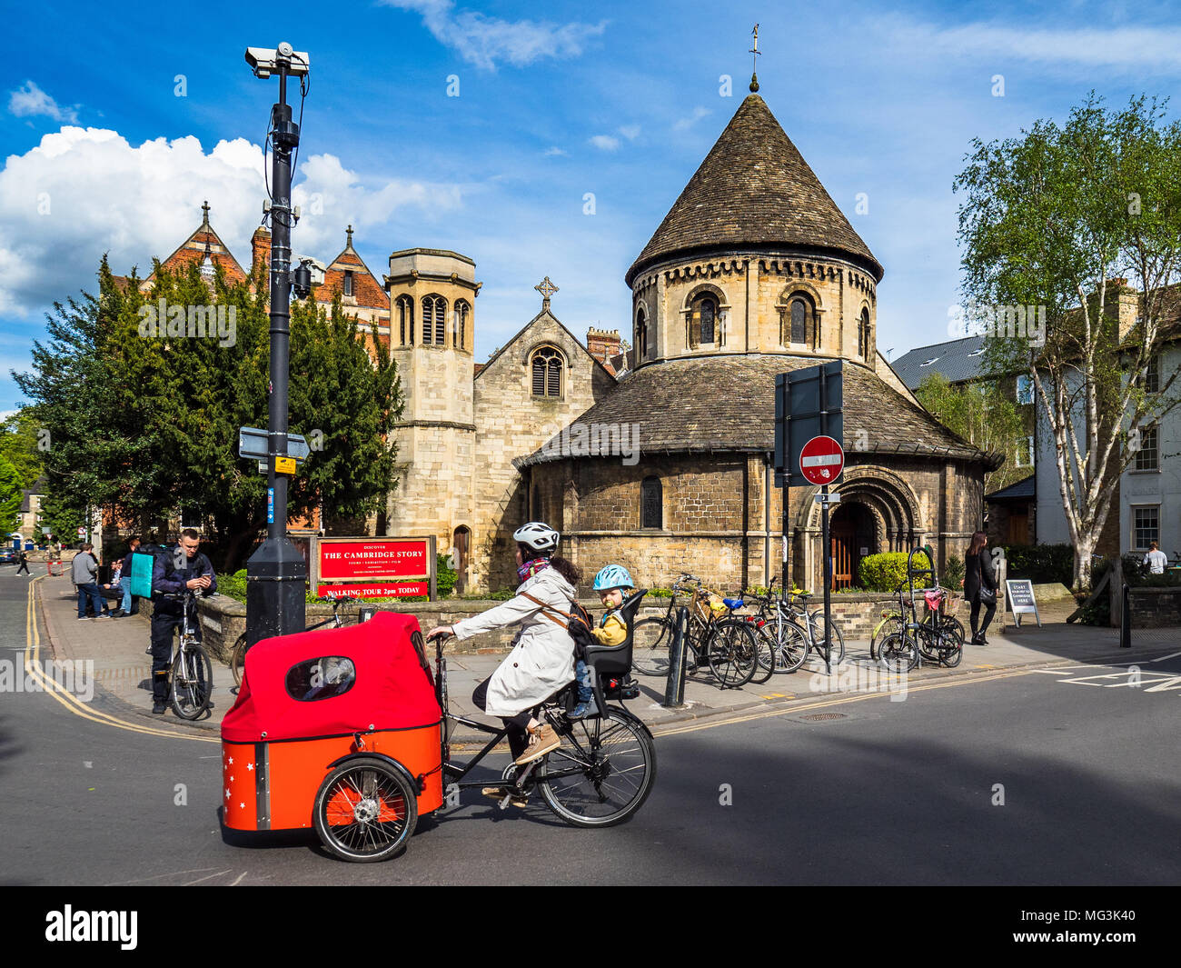 The Round Church Cambridge - Family on a cargo bike passa davanti alla storica Round Church, costruita intorno al 1130, nel centro storico di Cambridge UK. Foto Stock