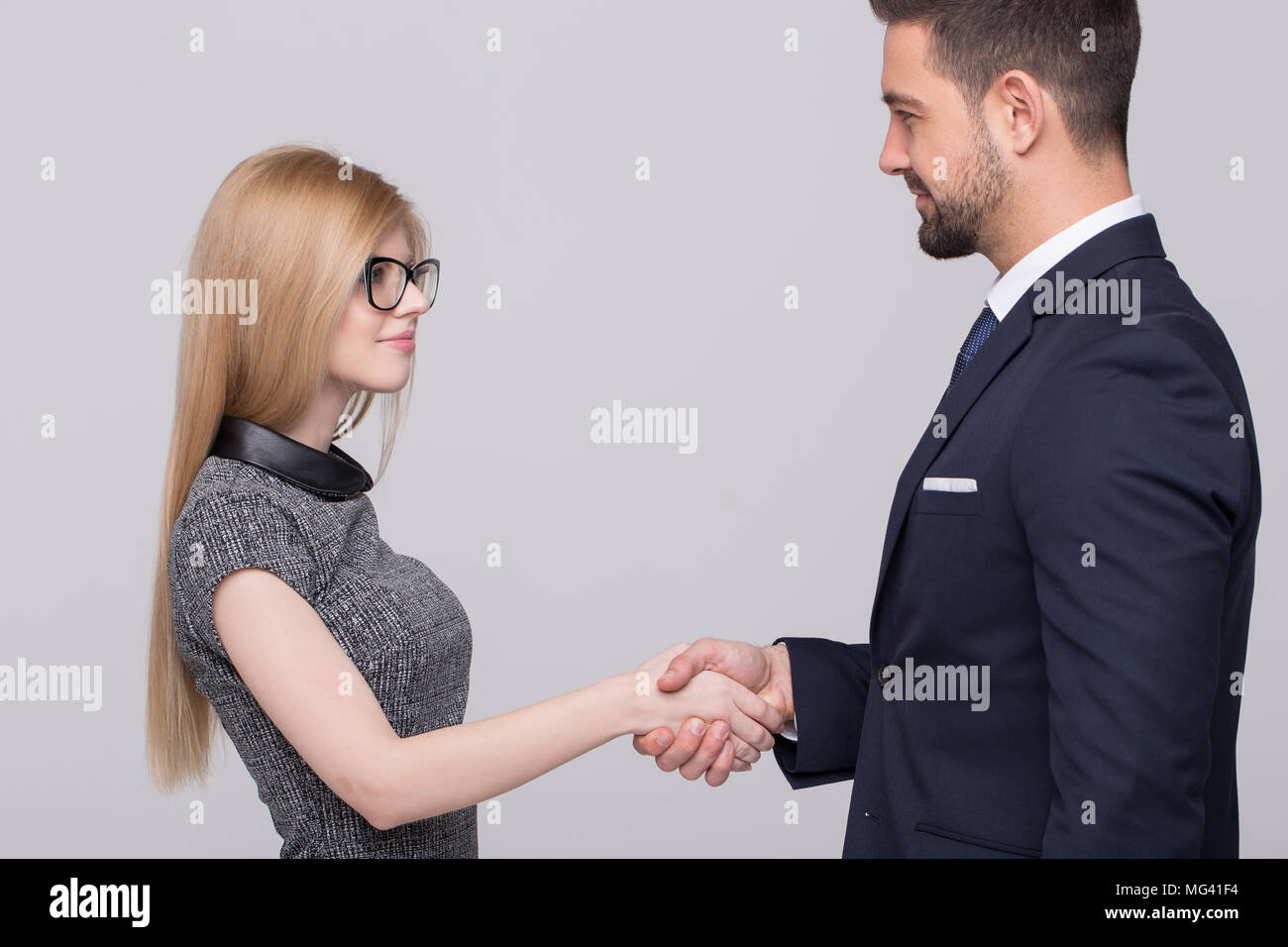 Professionale di giovani imprenditori caucasica handshake su sfondo grigio Foto Stock