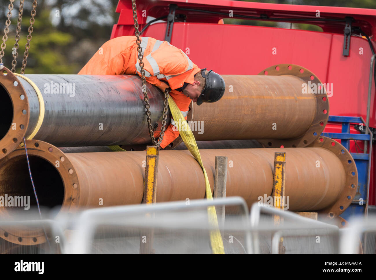 Costruzione maschio lavoratore di indossare abbigliamento protettivo e casco e la posa di nuove tubazioni nel Regno Unito. Foto Stock