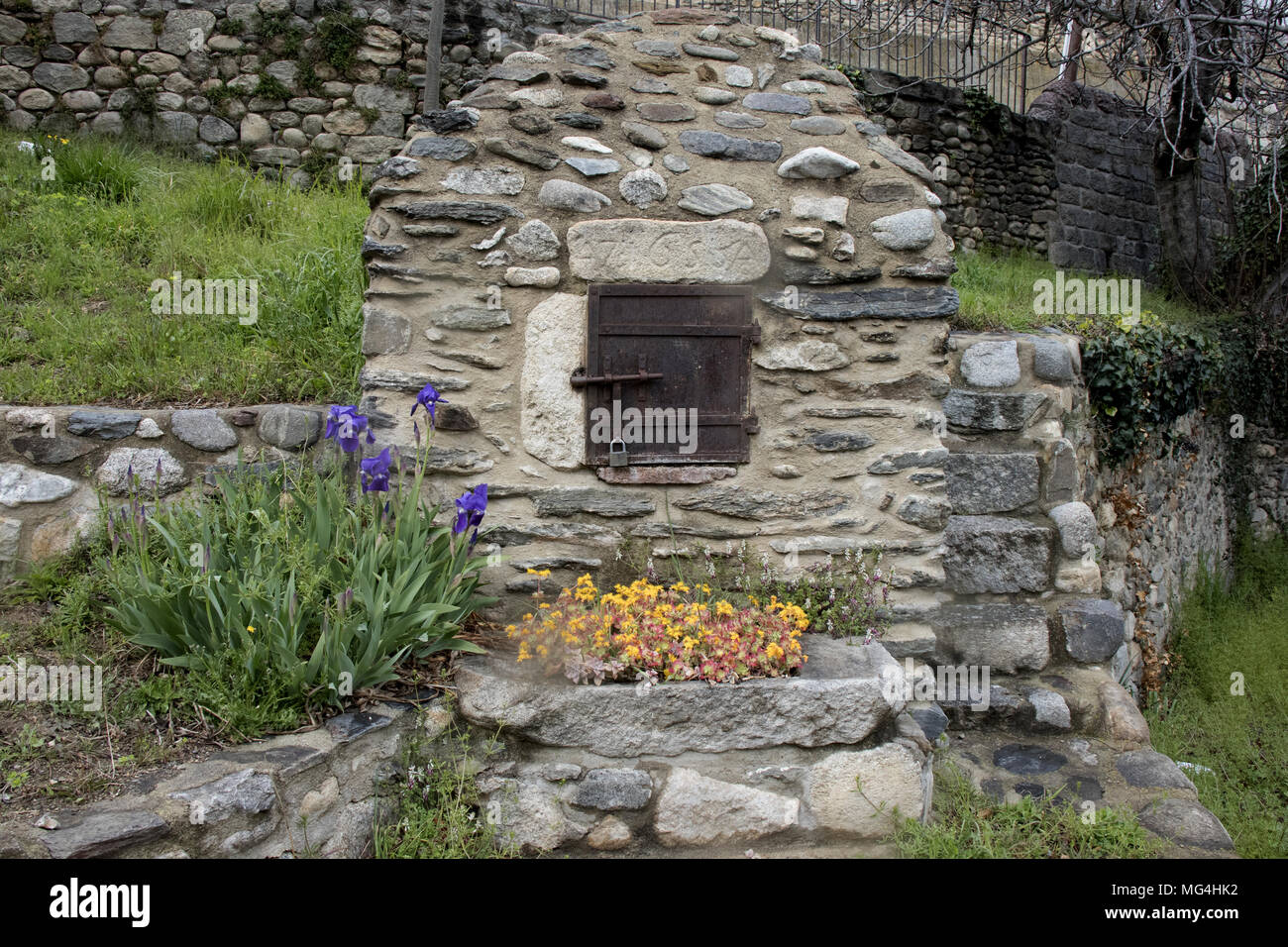 Antica pietra forno francese nel villaggio di Catllar, vicino a Prades, con sedum e iridi, Languedoc-Roussillon, Pyrénées-Orientales, Francia. Foto Stock