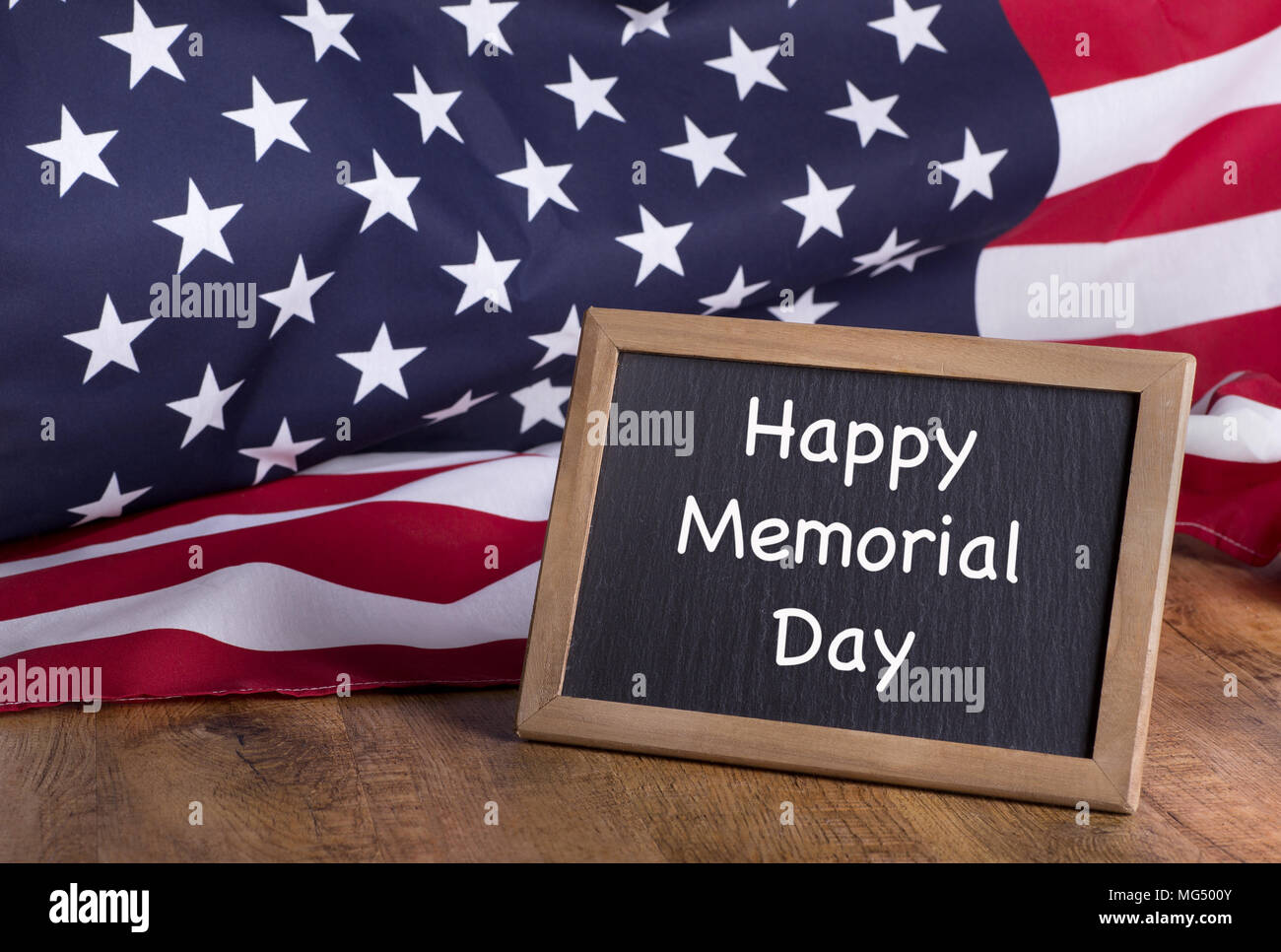 Felice giorno memoriale scritto su una lavagna con bandiera americana in background Foto Stock