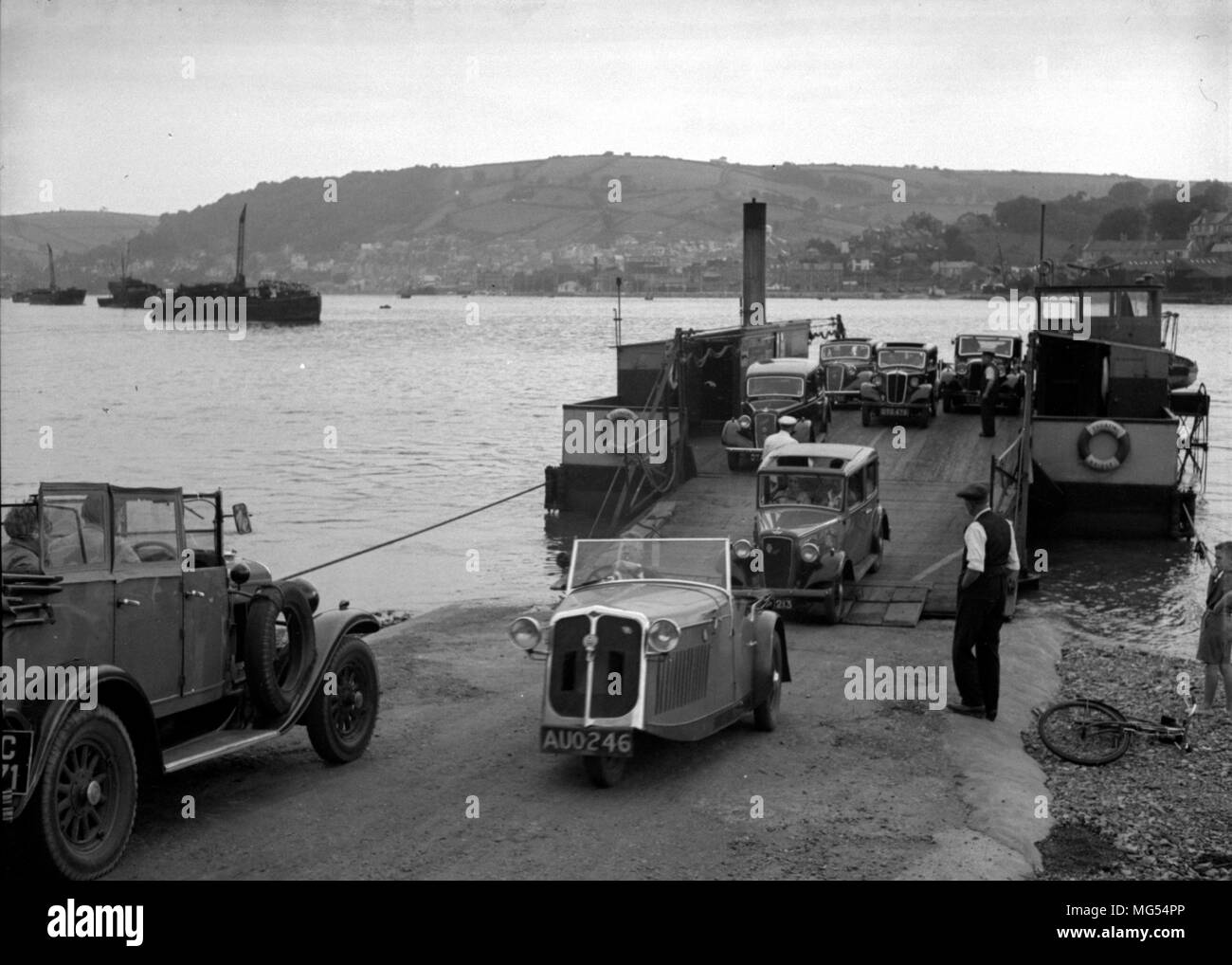 Un'auto a tre ruote Raleigh Safety t parte da un traghetto a Devon negli anni '30, circondata da auto d'epoca Foto Stock