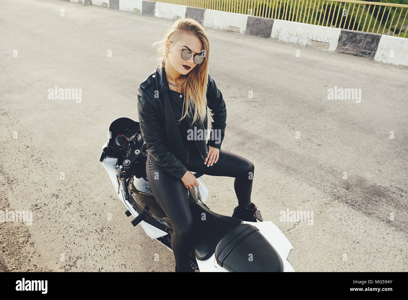 Bella donna biker in posa seduta su una moto Foto Stock