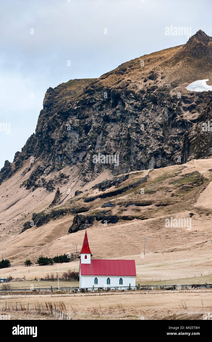 Reynisfjara, Sud dell'Islanda. Chiesa Reyniskirkja (1929) si distingue per la strada che conduce alla famosa spiaggia di sabbia nera Foto Stock