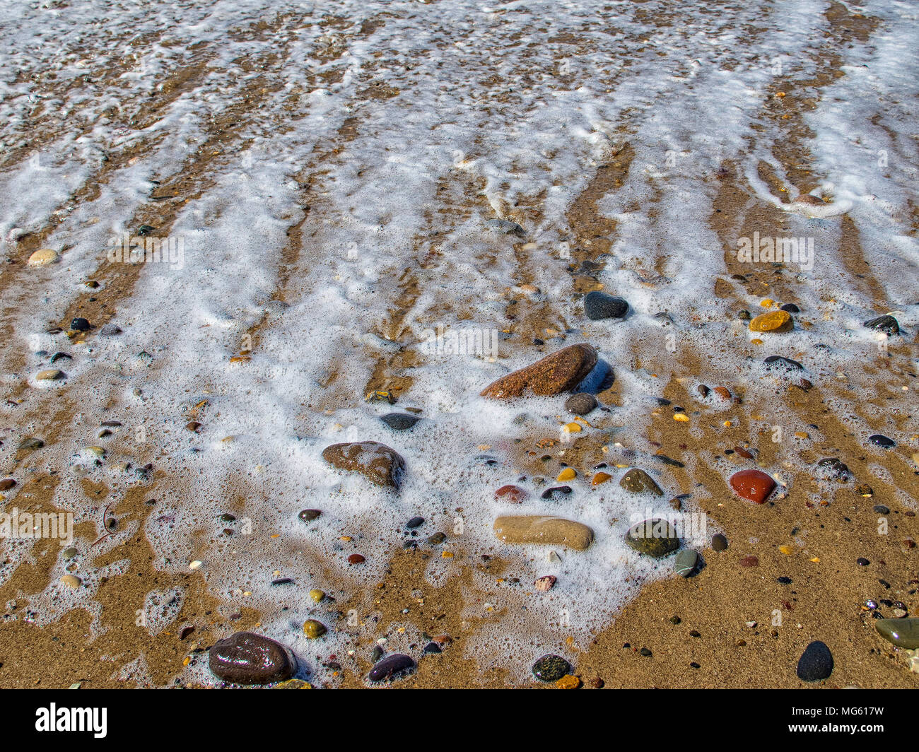 I ciottoli sulla spiaggia come un onda ritiri delicatamente creando un tranquillo e pacifico immagine Foto Stock