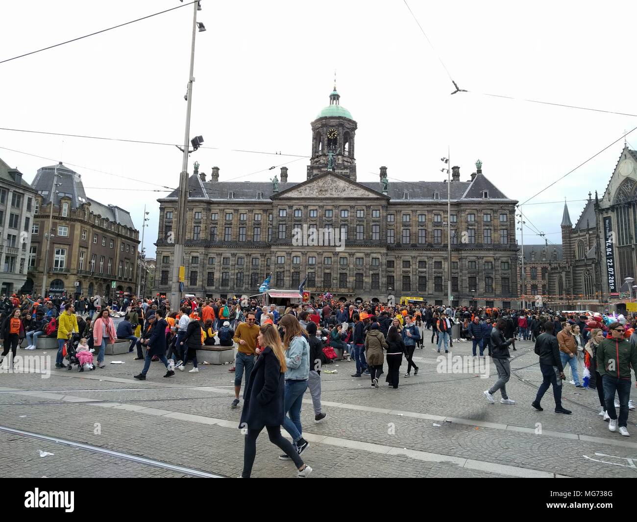Amsterdam, Paesi Bassi - Aprile 27th, 2018 : RE del giorno - gruppo di persone di fronte alla famosa piazza; King's Day (precedentemente noto come Festa della Regina) festeggiamenti invitare la gente del posto e turisti in ammollo fino ad Amsterdam open-air divertente. Nelle strade, canali, parchi e ovunque, la città è ricca di arancia come Amsterdammers godere del più grande partito di strada dell'anno.; il credito: Bala Divakaruni/Alamy Live News Foto Stock