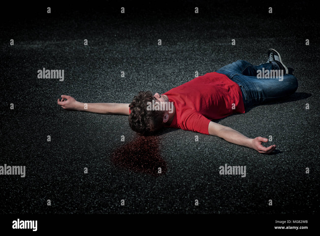 Scena del crimine - dead teen boy corpo nel sangue su asfalto - foto di scena. Il corpo di un giovane childlying sulla strada. Foto Stock