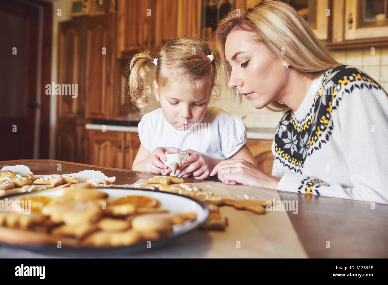 Mamma e figlia decorare i biscotti di Natale con zucchero bianco Foto Stock